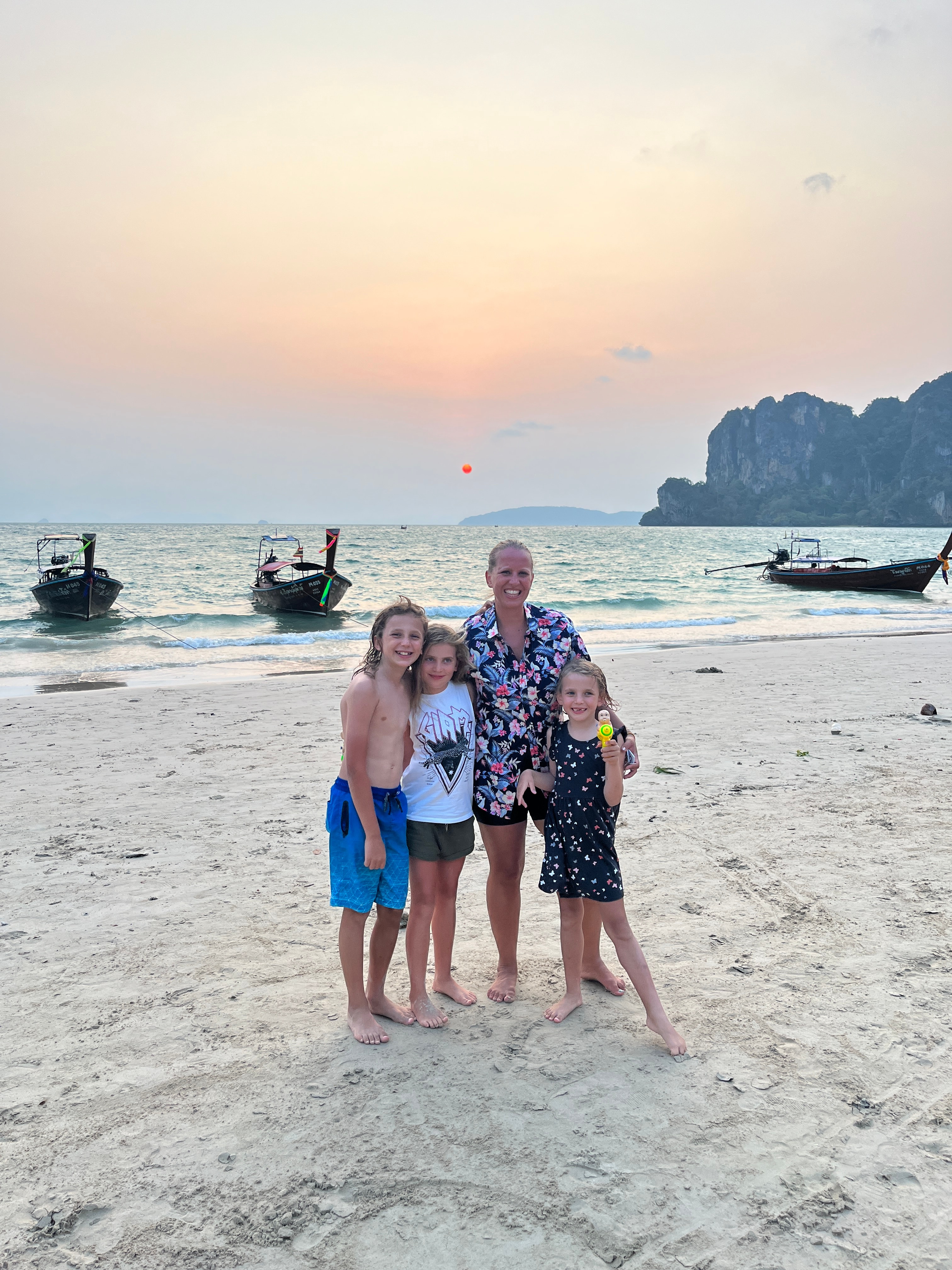 Advisor and her family with their arms around each other, posing together on a beach at sunset