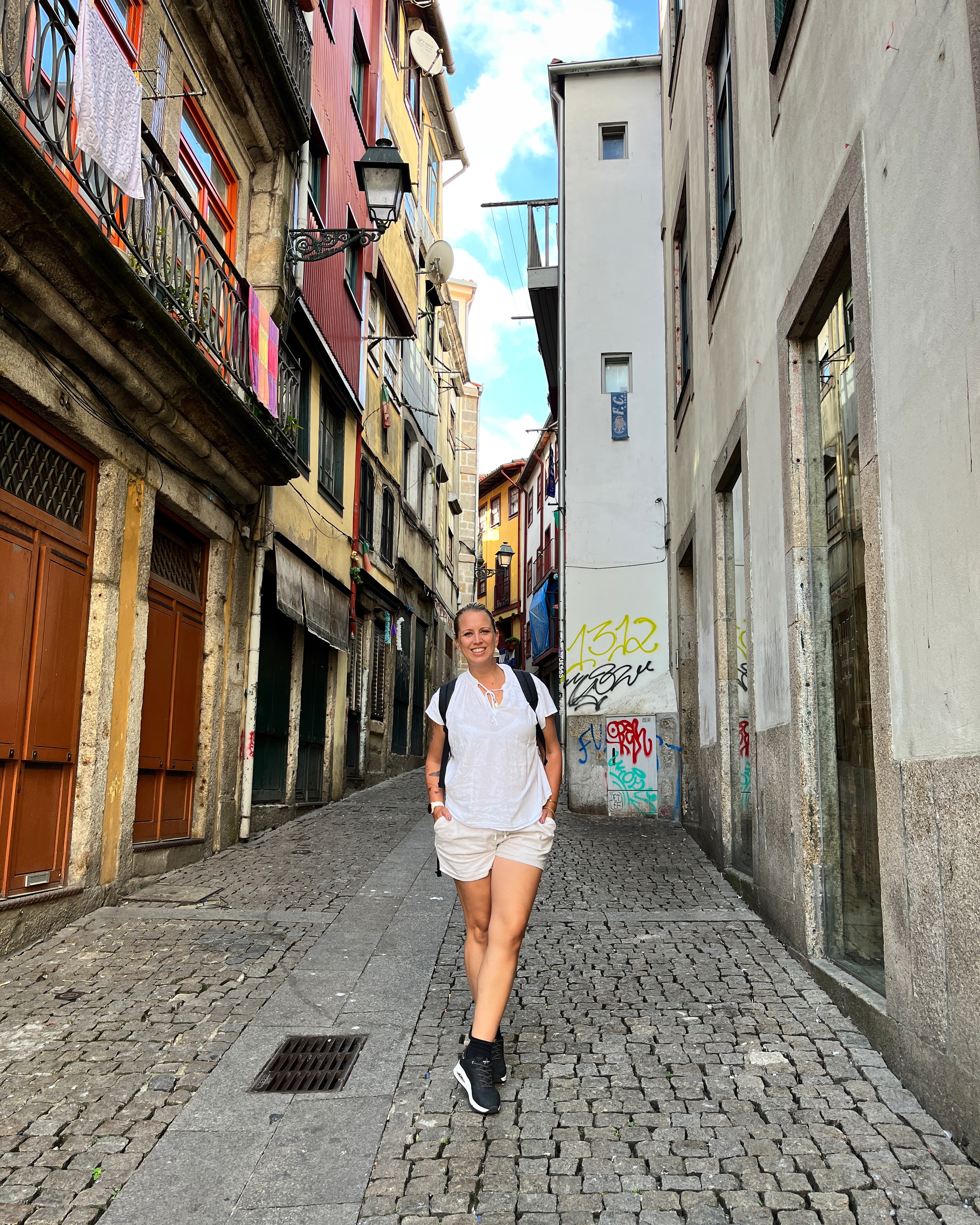 Advisor in white shorts and a t-shirt waking down a narrow cobblestone city street during the day