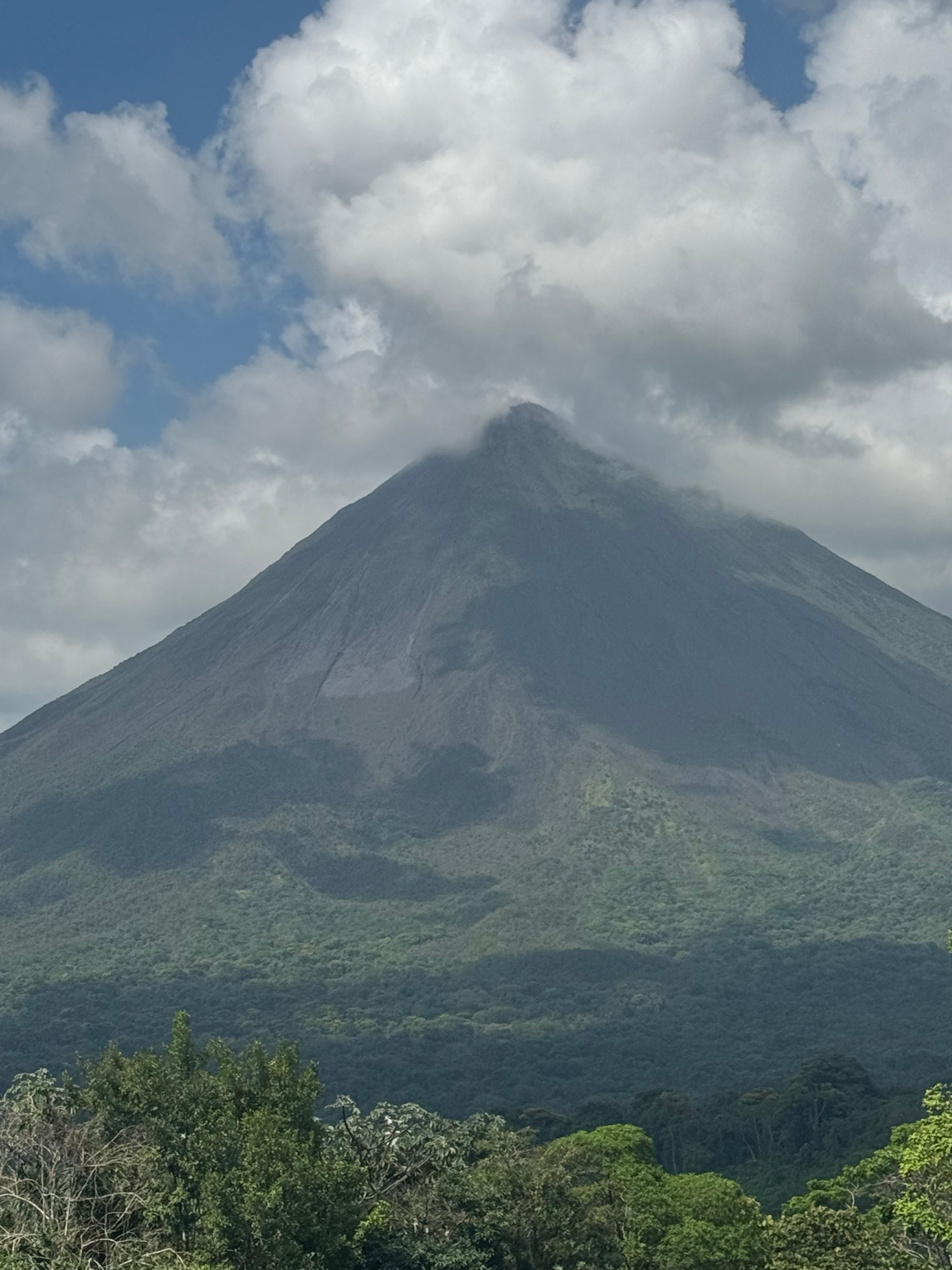 View of a solitary mountain rising above a green valley with puffy clouds above