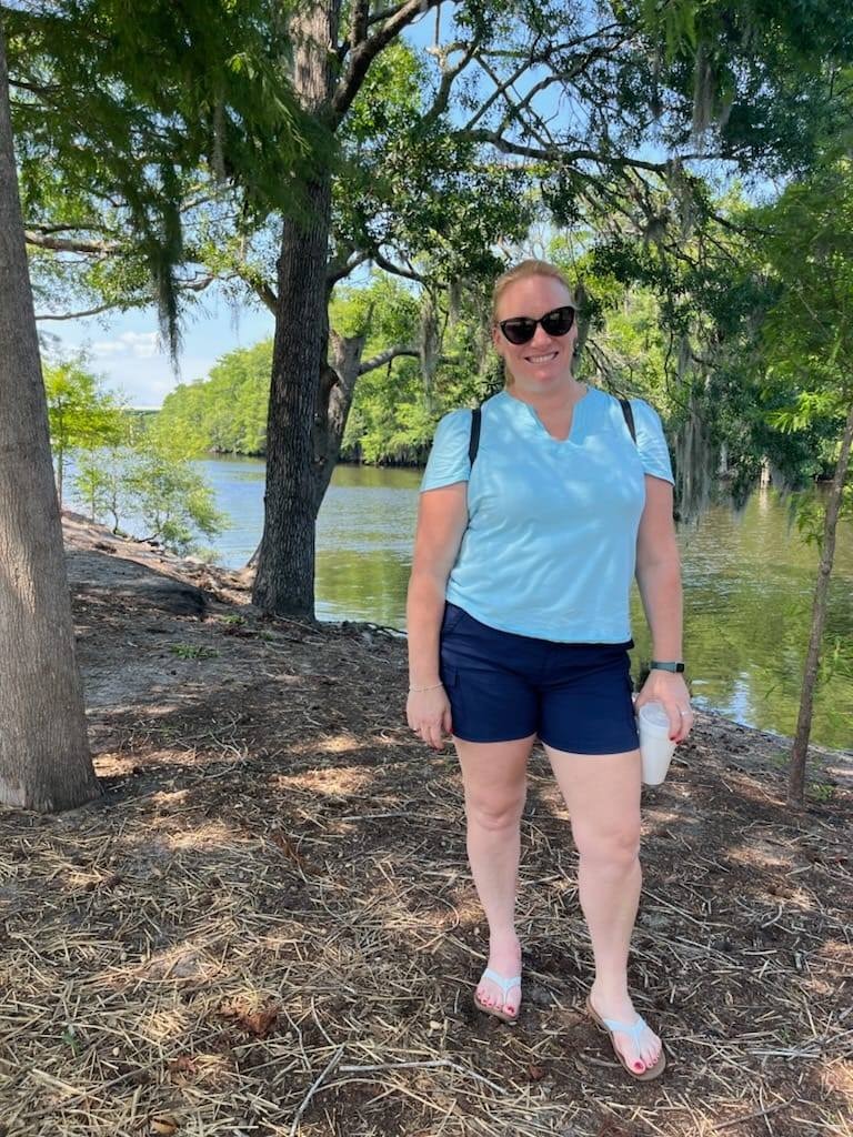 Advisor standing by the water under the shade of nearby trees