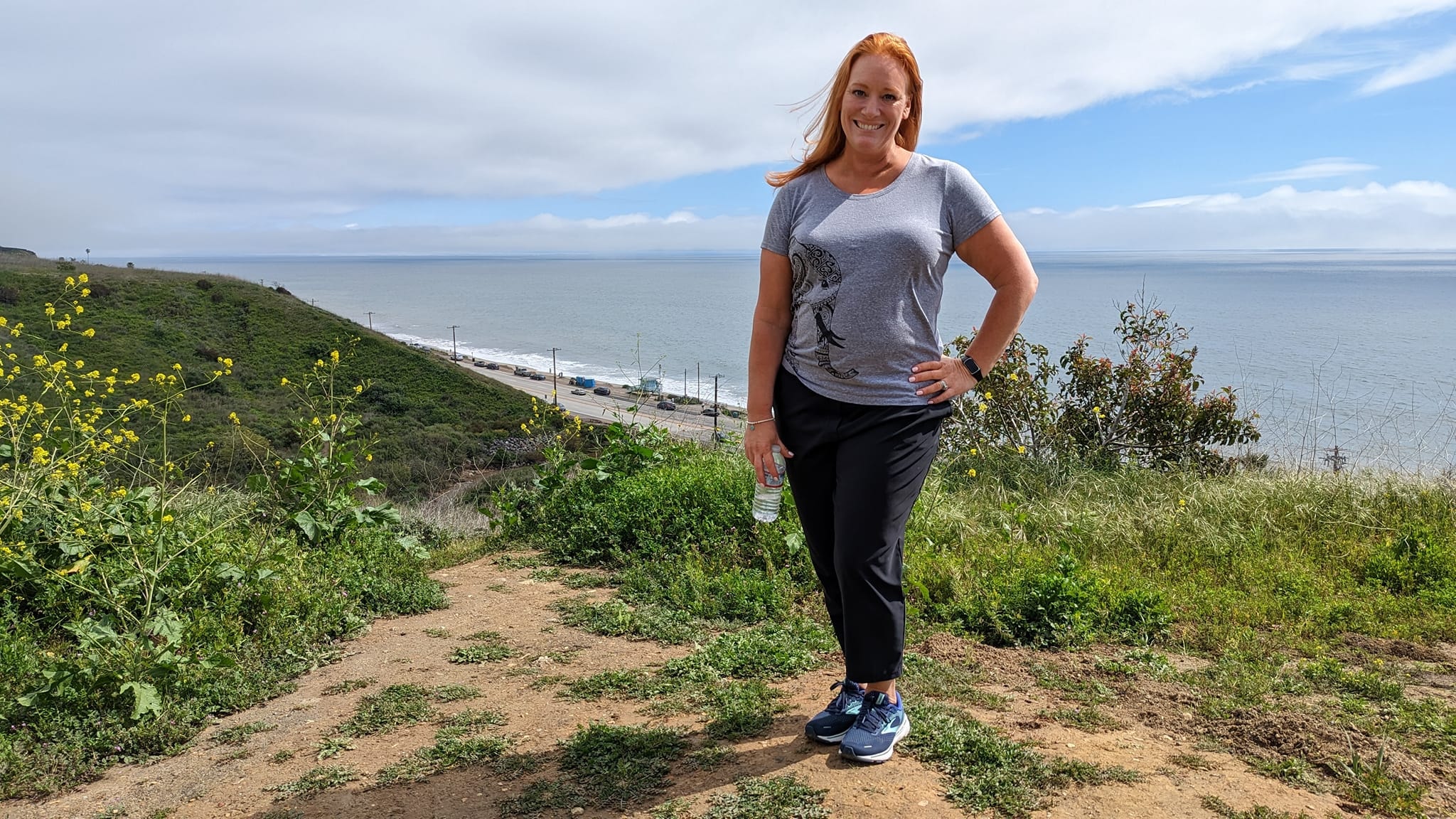 Advisor with hand on hip at a viewpoint overlooking a coastline