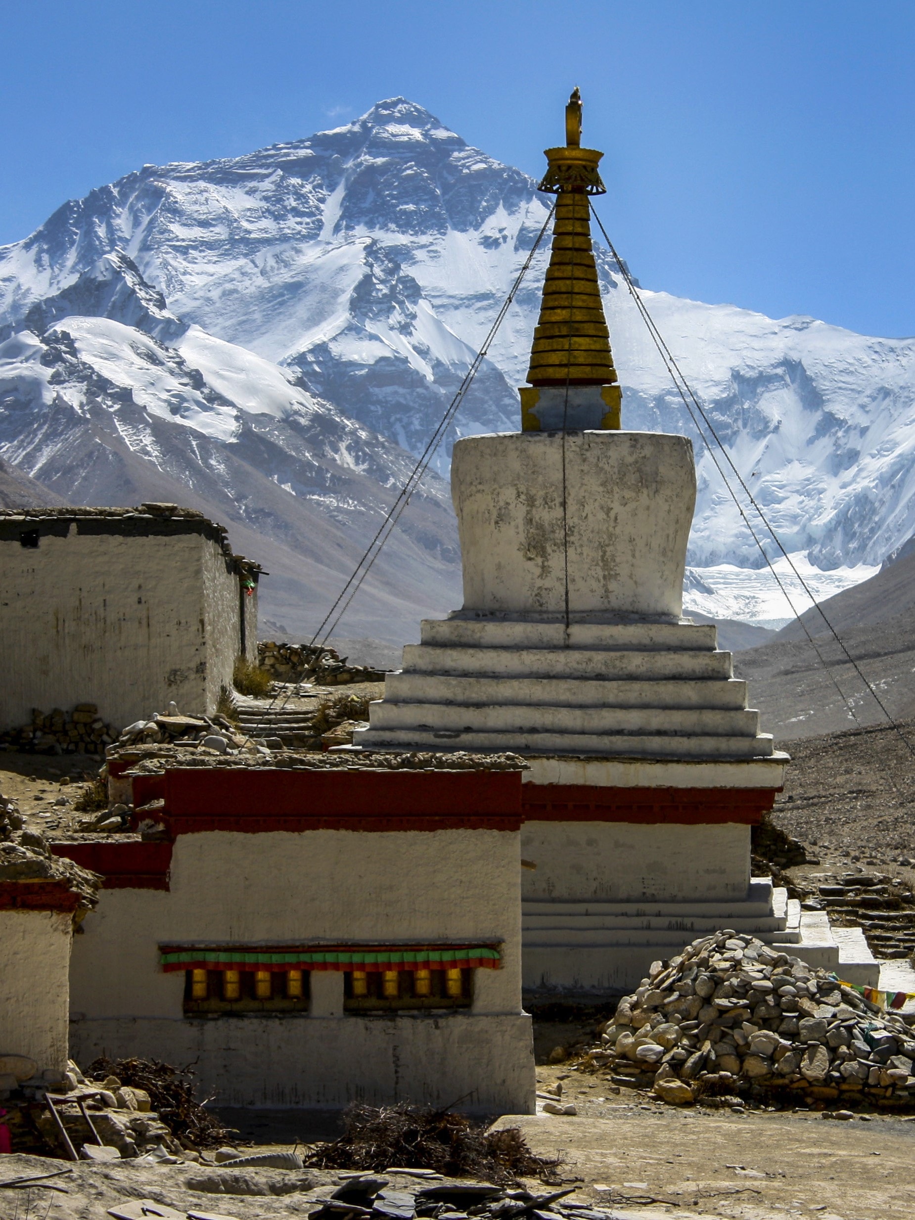 View of a statue at the base of a stunning snowy mountain under clear skies