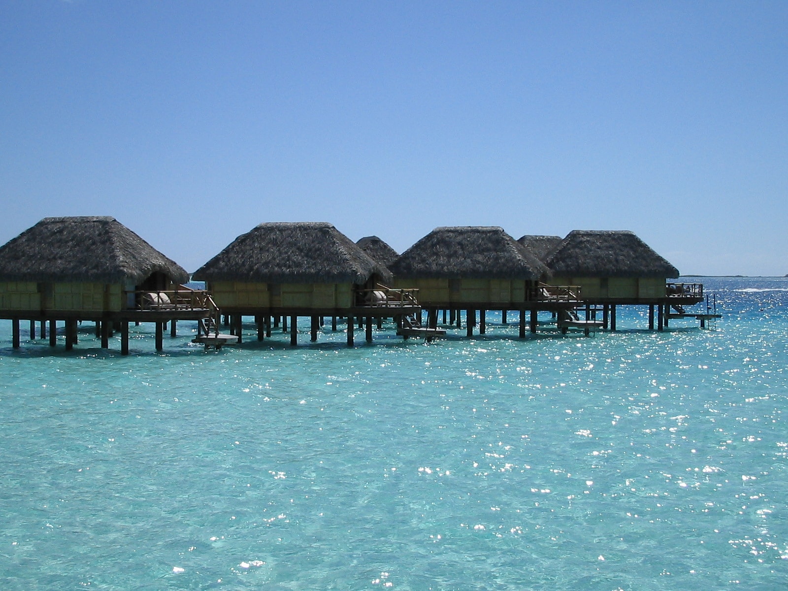 View of several overwater bungalows on a clear day