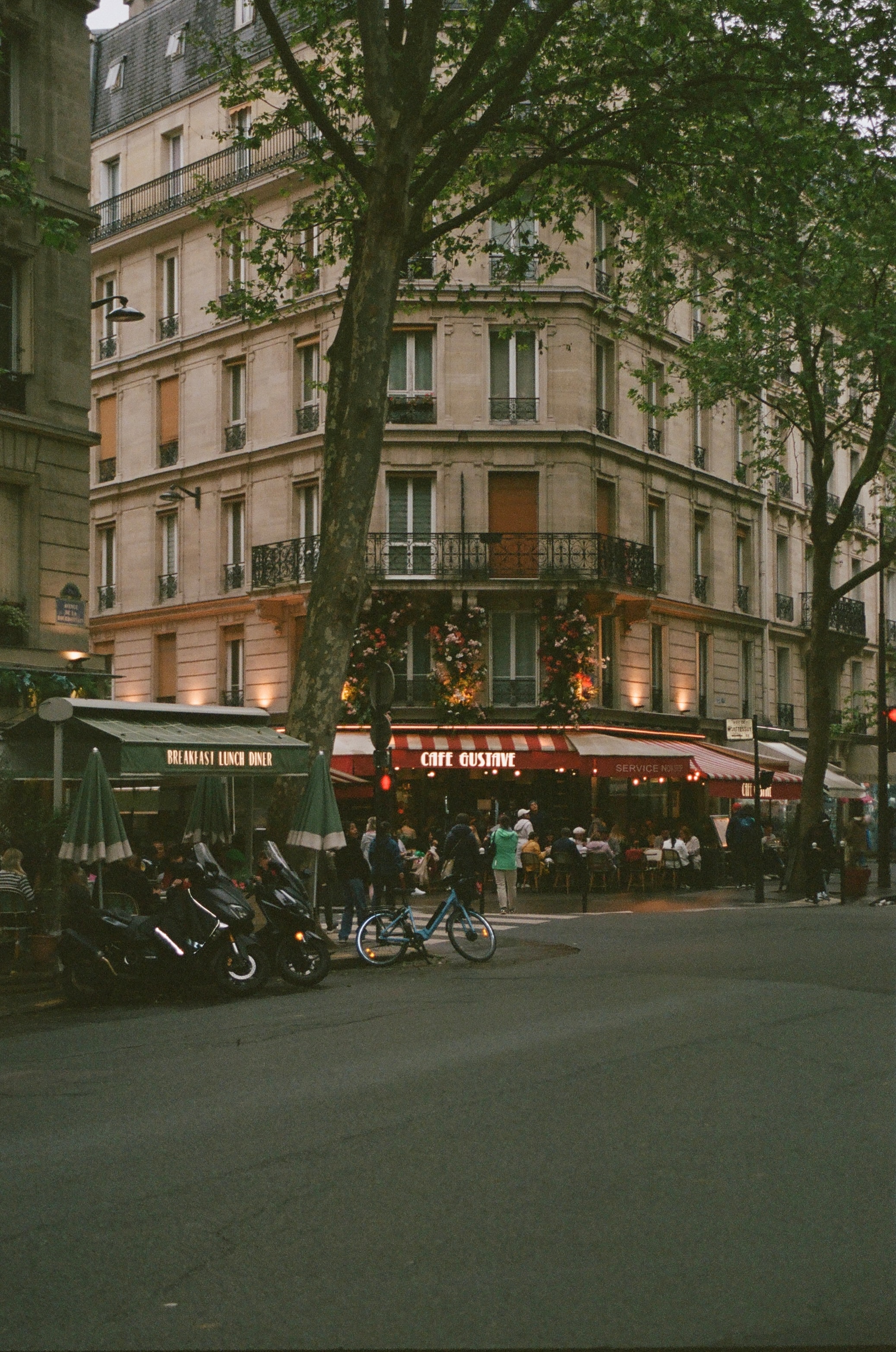 View of a bistro in Paris with a red awning as seen from across the street at dusk