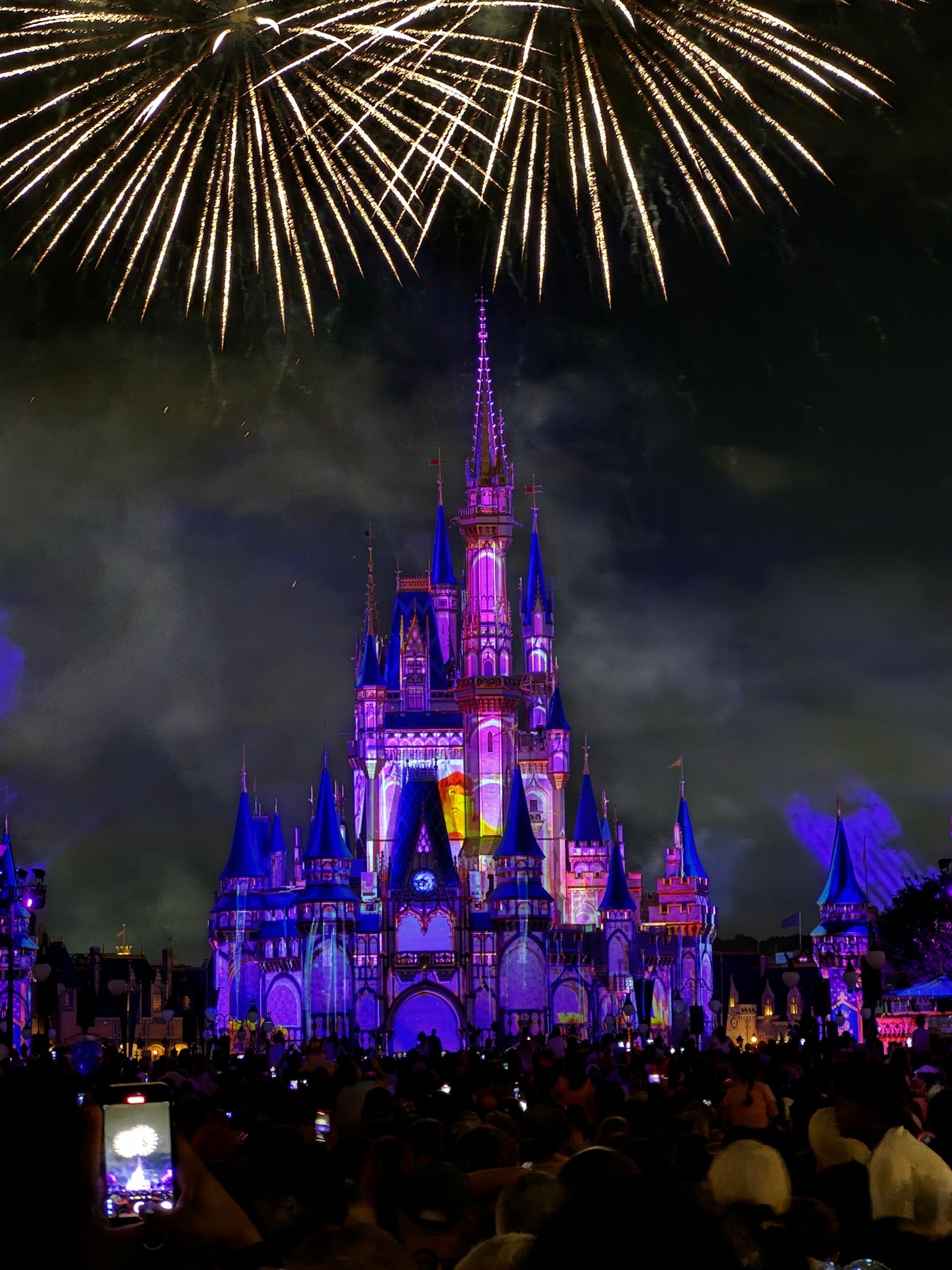 Cinderella’s castle lit up purple at night with fireworks in the sky