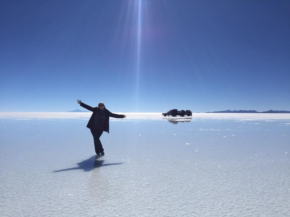 Advisor posing with arms outstretched on a icy tundra under clear skies