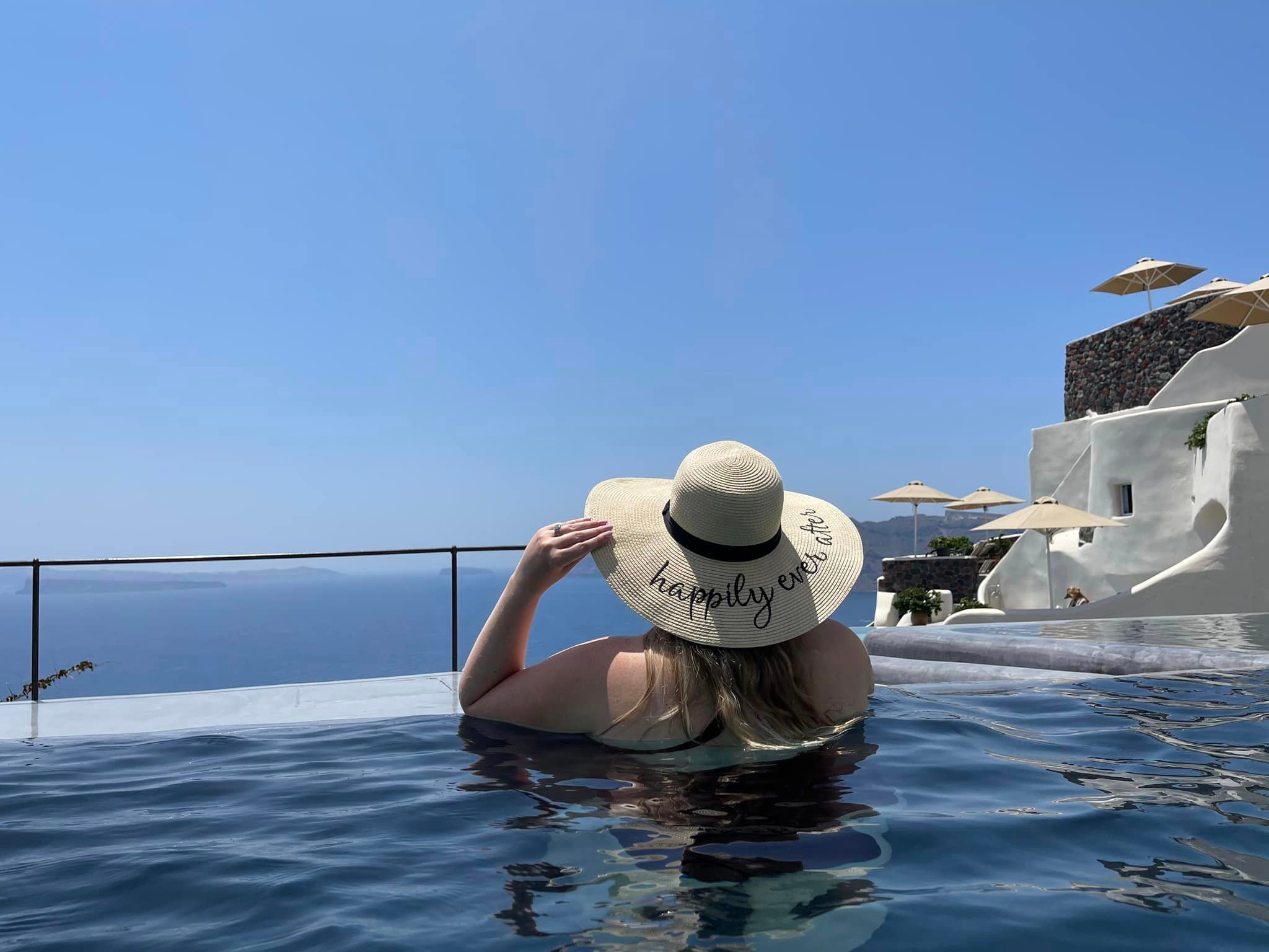 Advisor wearing a sun hat in an infinity pool overlooking the sea on a sunny day