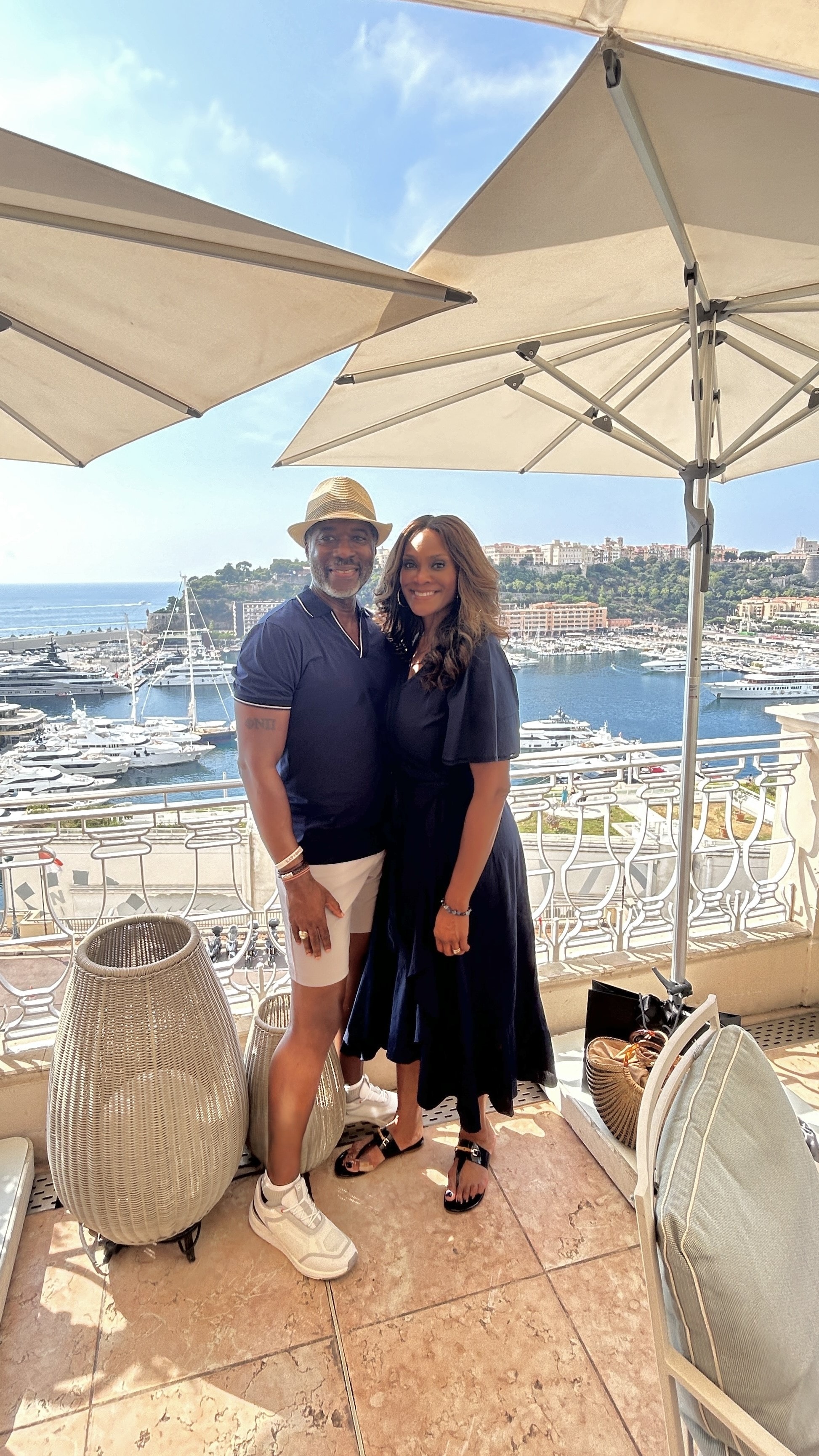 Advisor and partner side by side on a balcony overlooking a marina on a sunny day