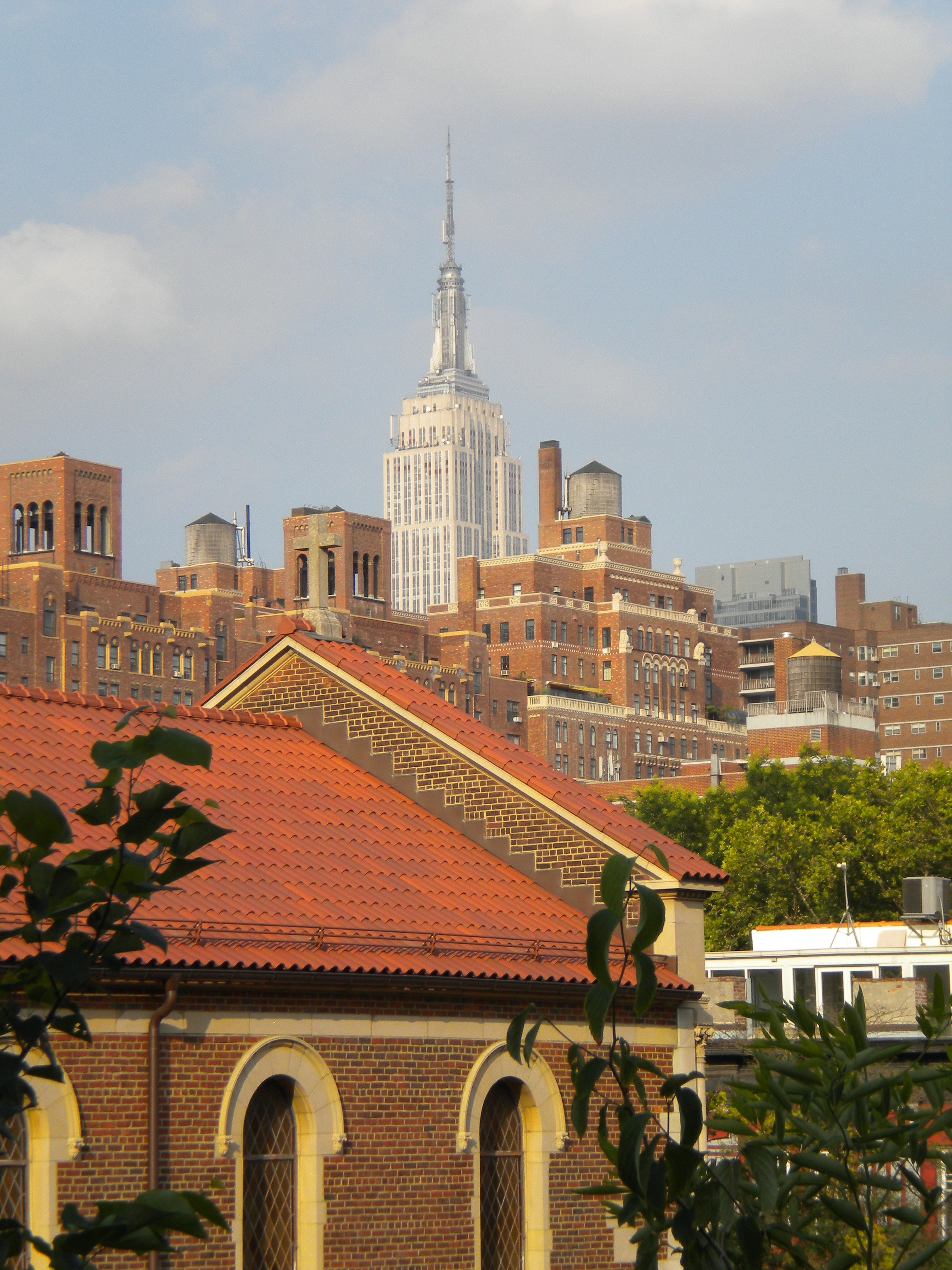 A view looking across a city at a tall tower, the Empire State Building, on an overcast day.