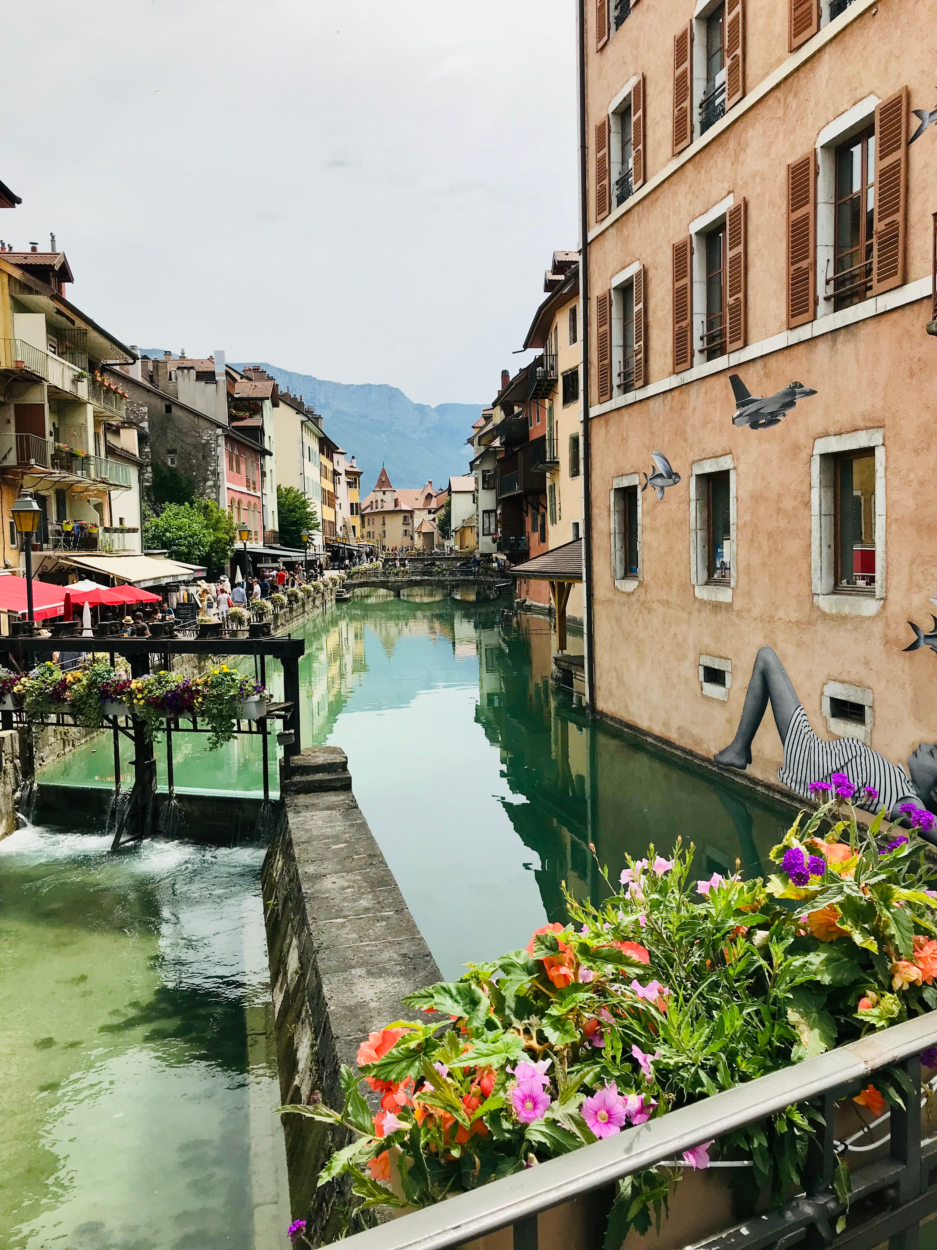 A view of a canal with flowers in a planter box on a sunny day. 