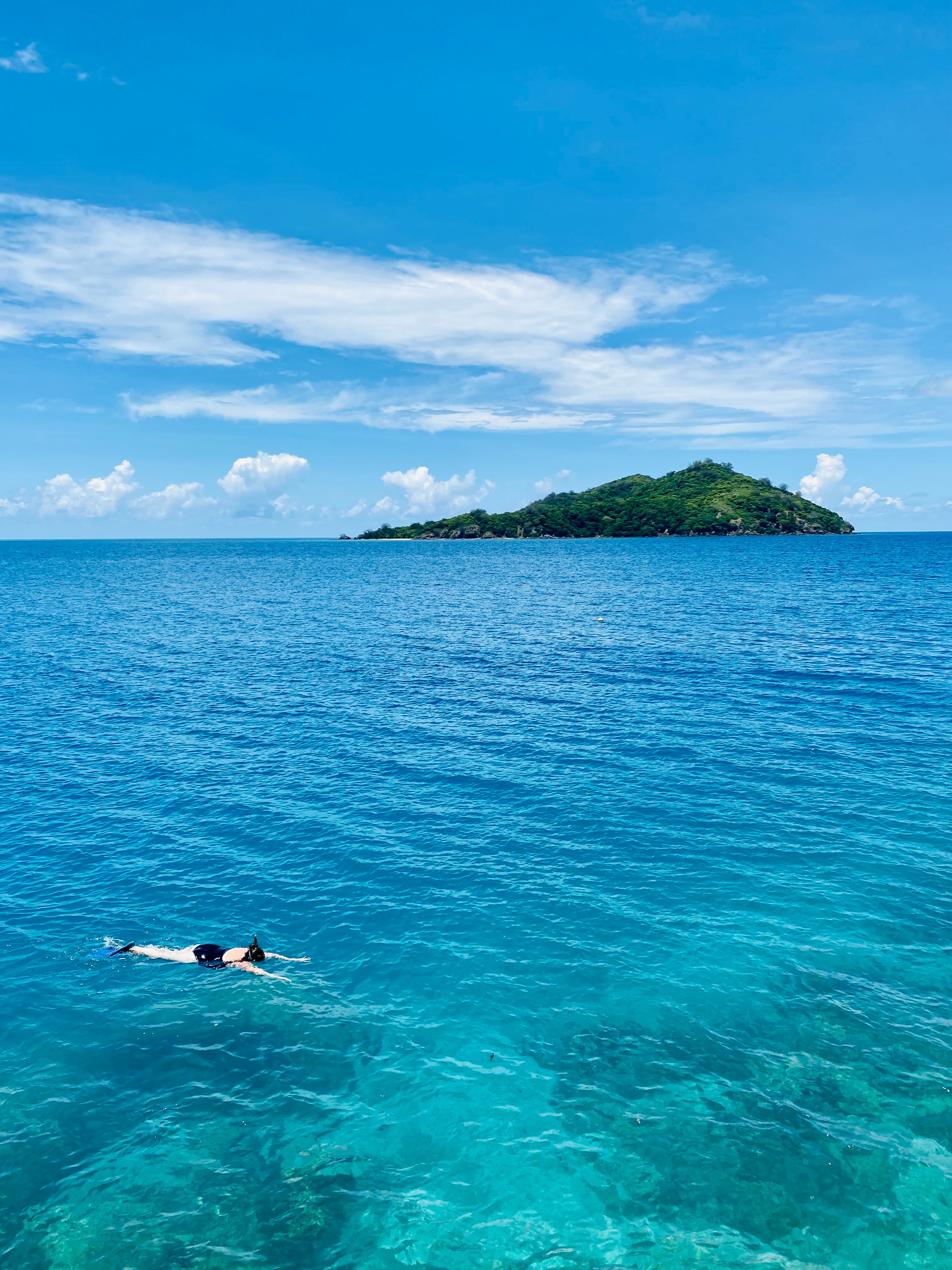 A view of the ocean with an island in the distance on a sunny day. 