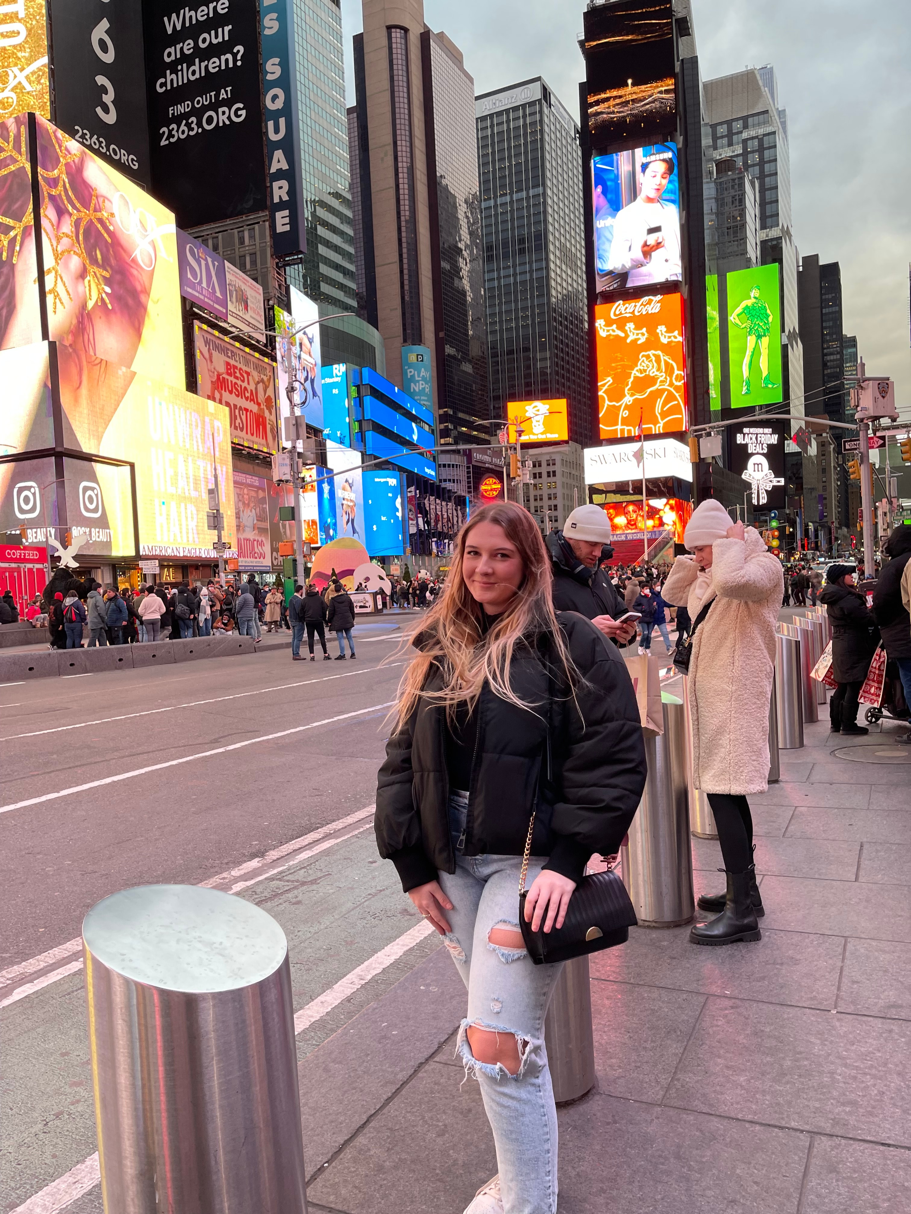 Advisor posing on a bustling corner of Time's Square on a cloudy day. 