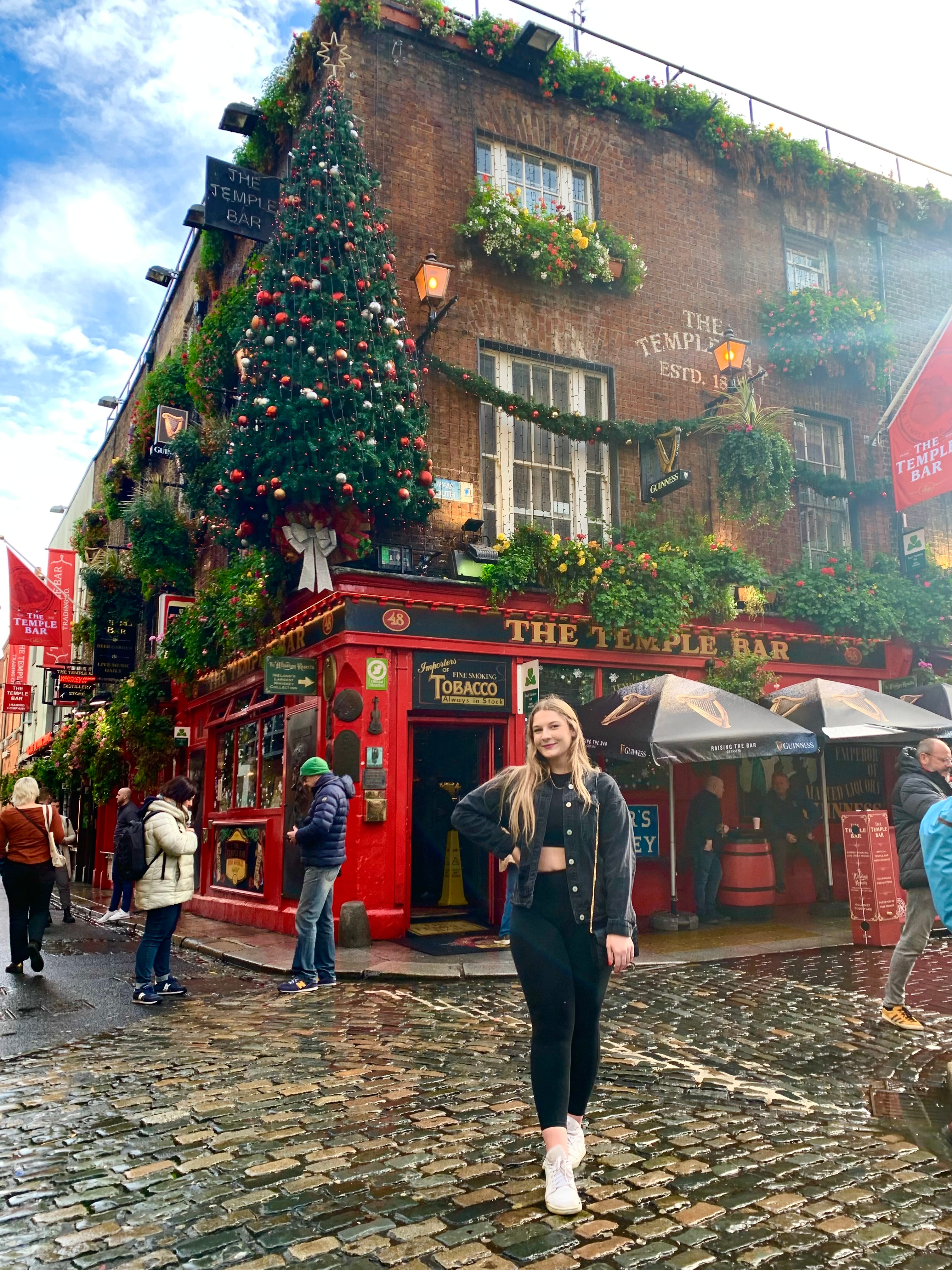 Advisor posing on bustling street corner decorated for the holidays. 