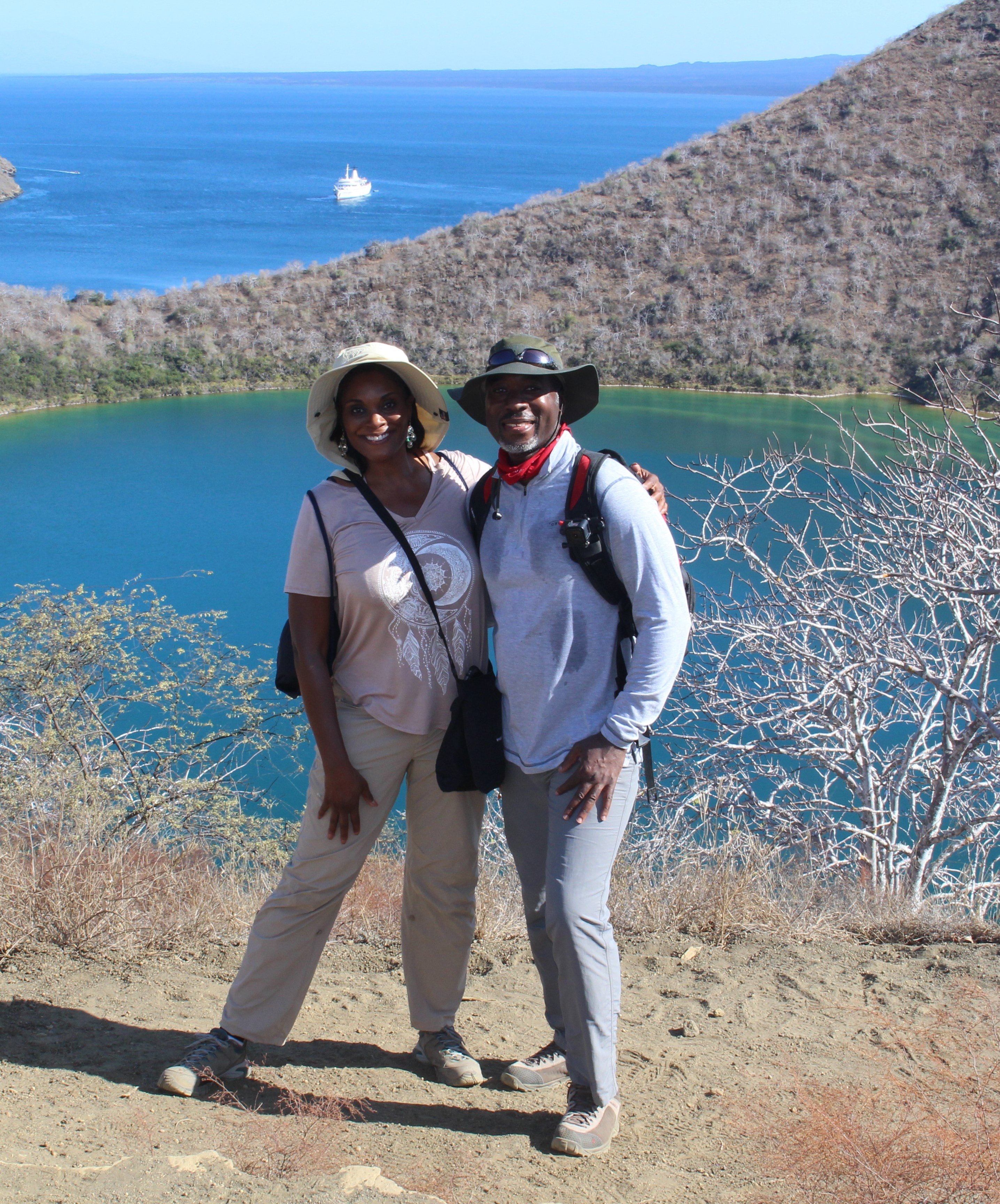 Advisor and a woman side by side on a hike with the ocean visible behind them 