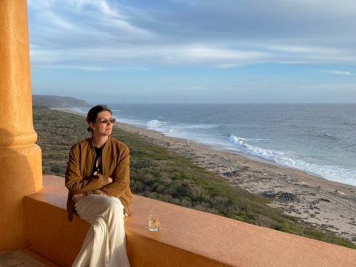 Advisor sitting on a ledge overlooking a beautiful empty beach