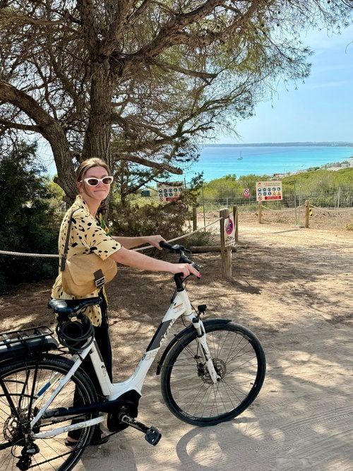 Advisor with a white bicycle on a path by the sea on a sunny day