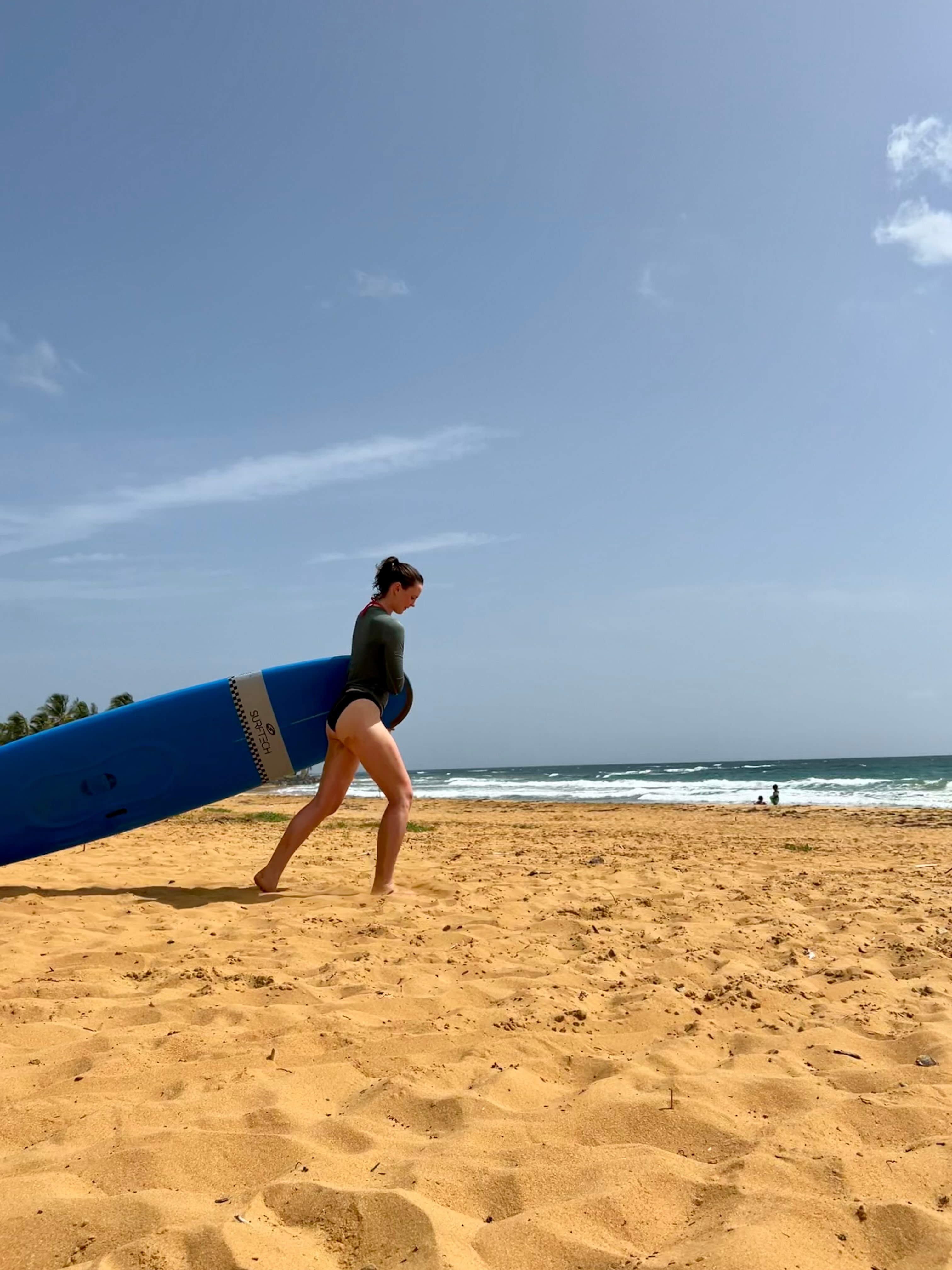 Advisor walking on the beach with surfboard in hand