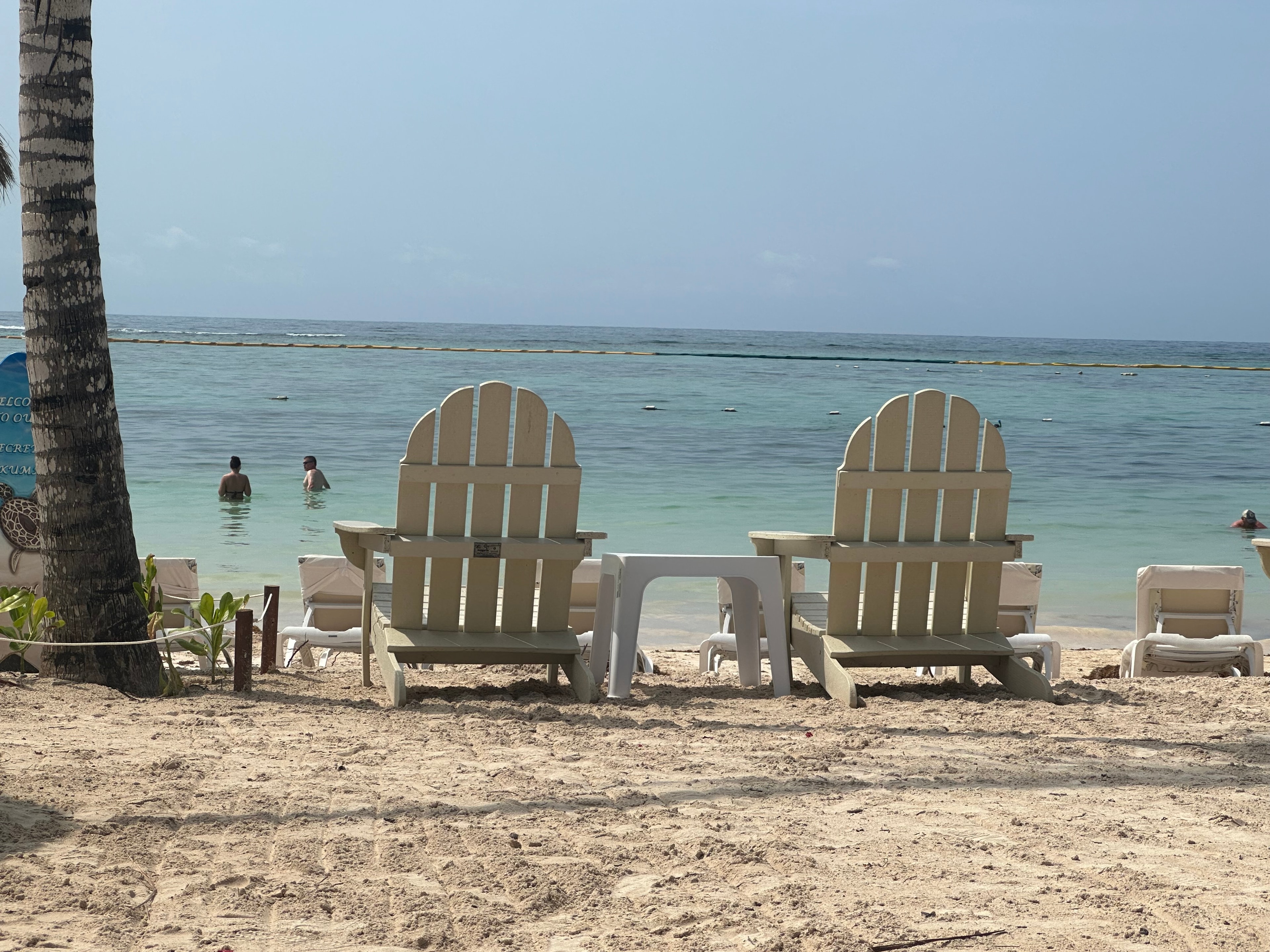 Beach chairs face the ocean as waves lap the shore on a sunny day. 