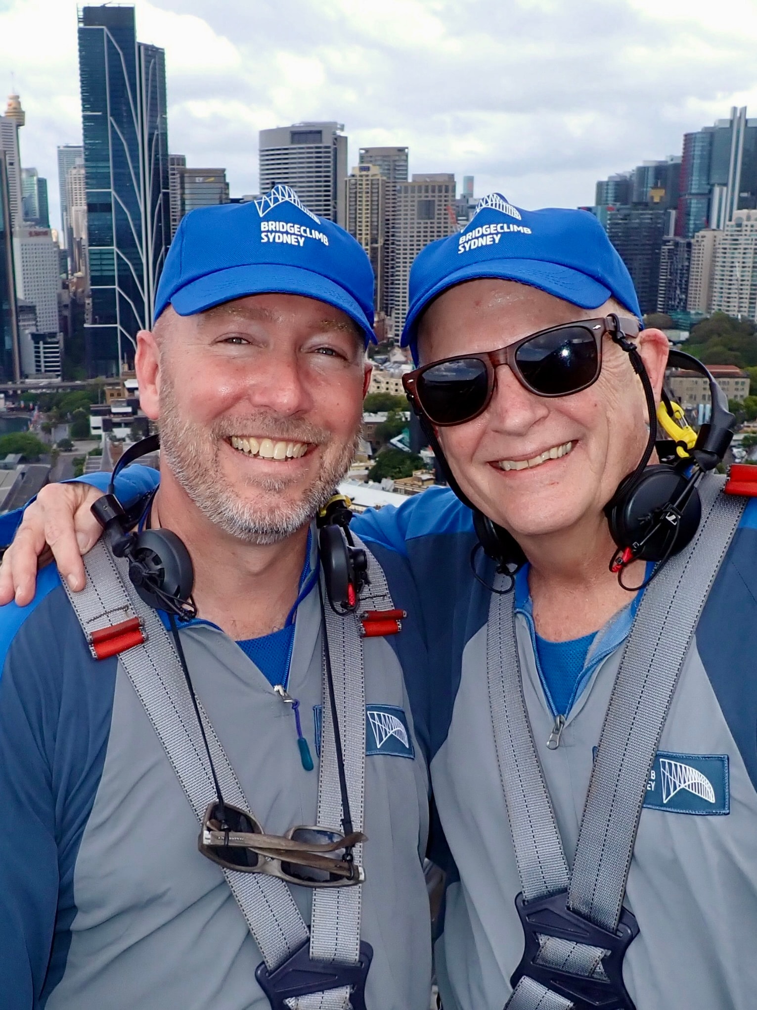 Advisor posing for an image with a friend during the daytime with a city in the distance. 