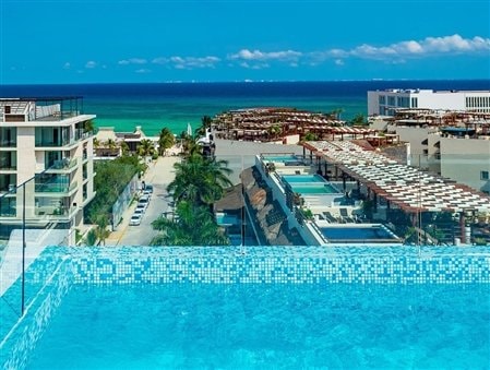 A swimming pool view over looking other buildings in front of a body of water during the daytime