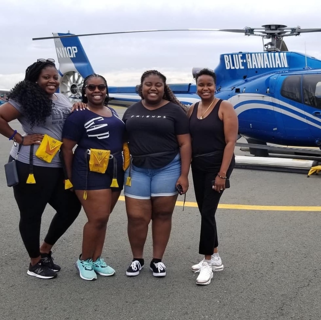 A group of girls posing outside of a helicopter. 