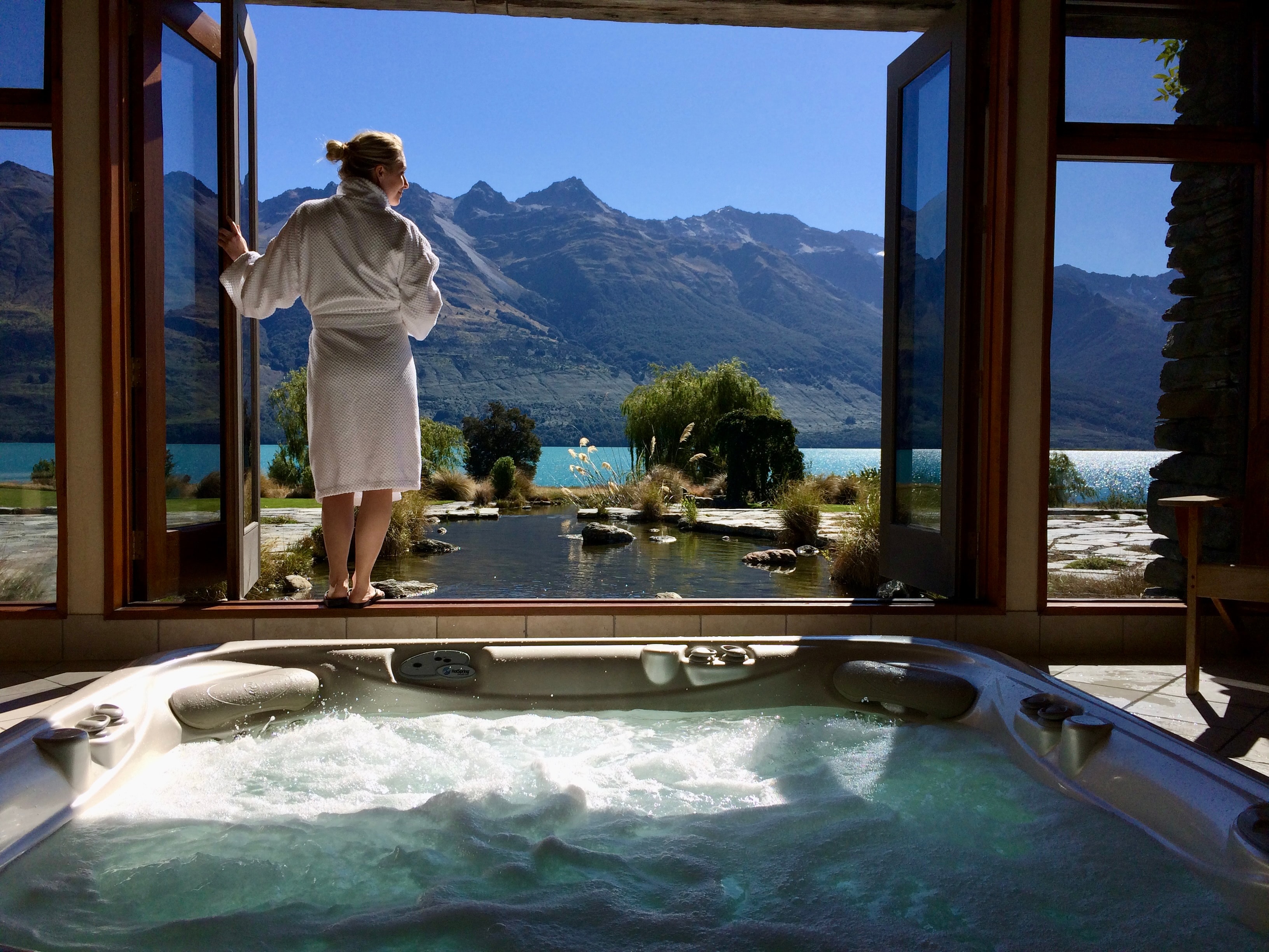 A woman standing in a window with a pretty view. 