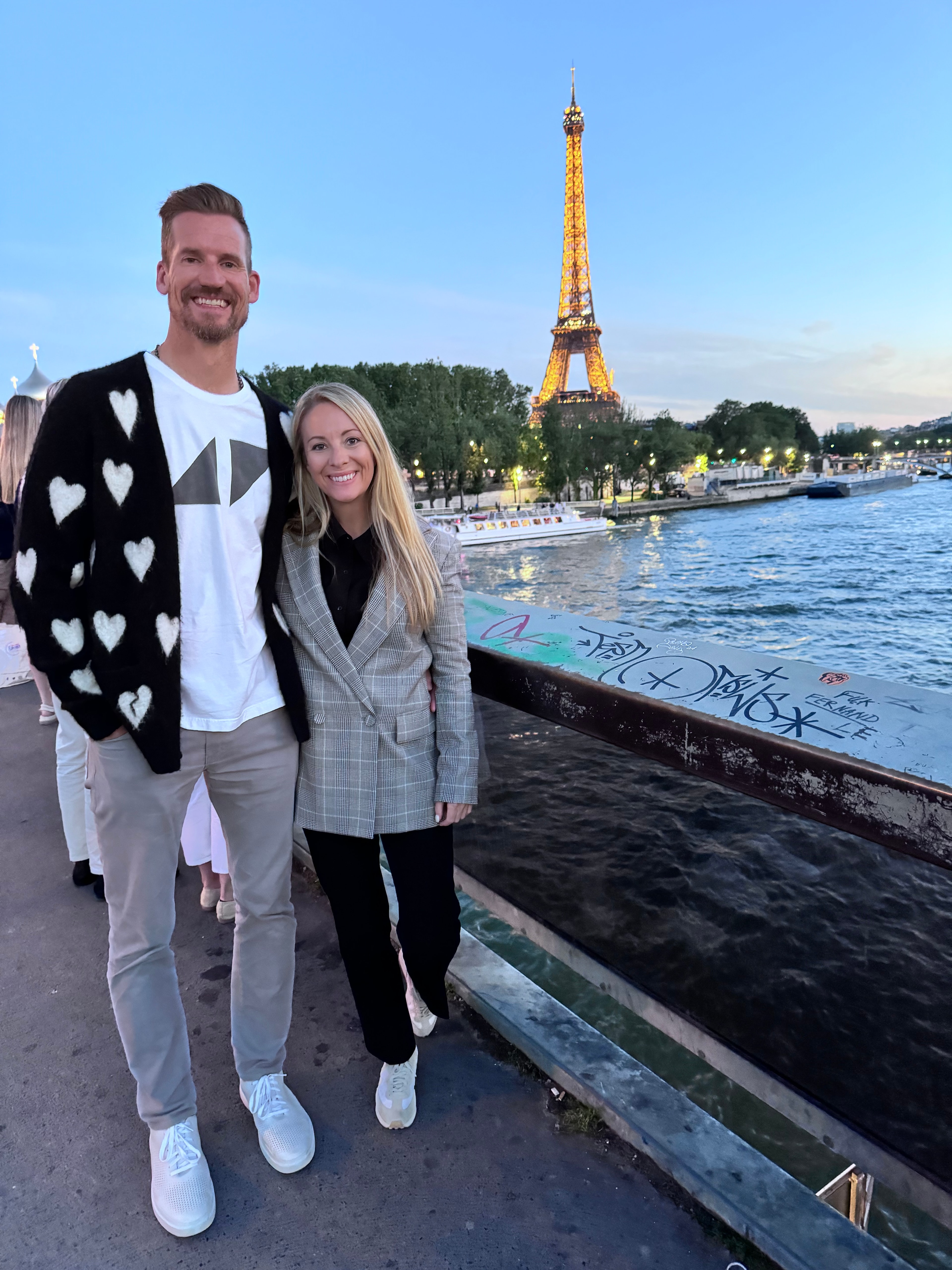 A couple posing with a waterway and Eiffel Tower in the distance. 