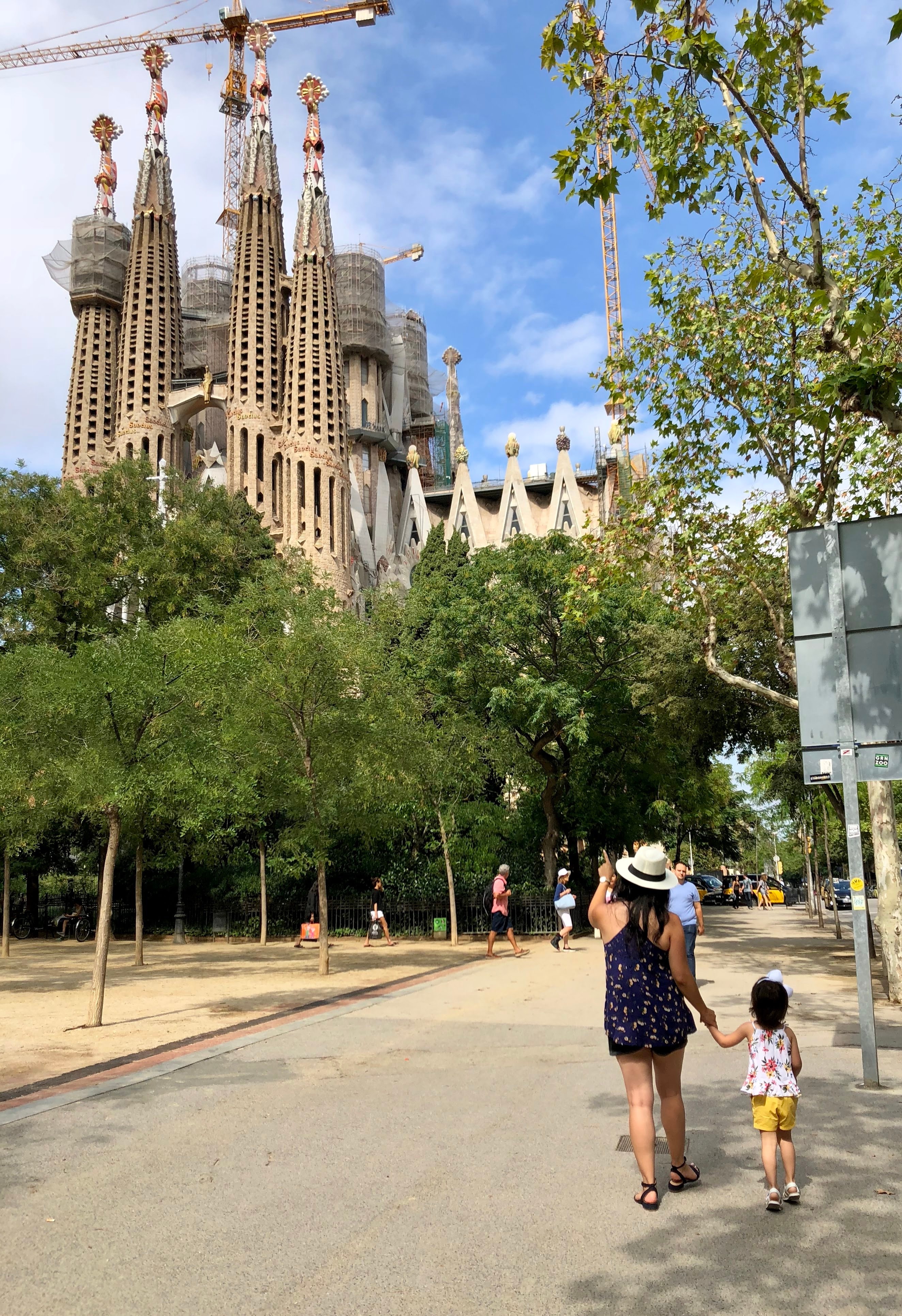 View of a park pathway with the Sagrada Familia cathedral in Barcelona on a sunny day in the background