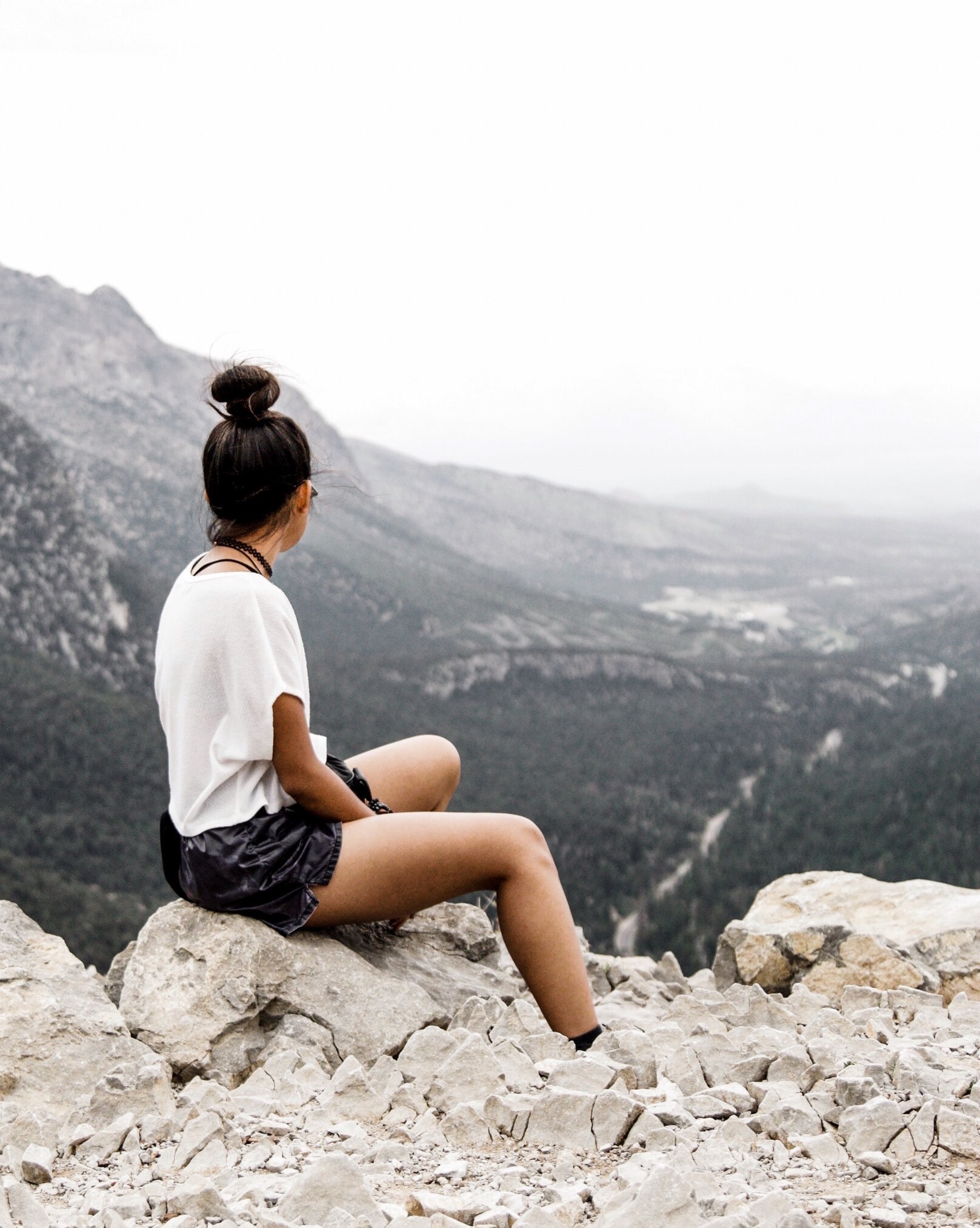 Advisor sitting on a rock overlooking a dark valley on a cloudy day