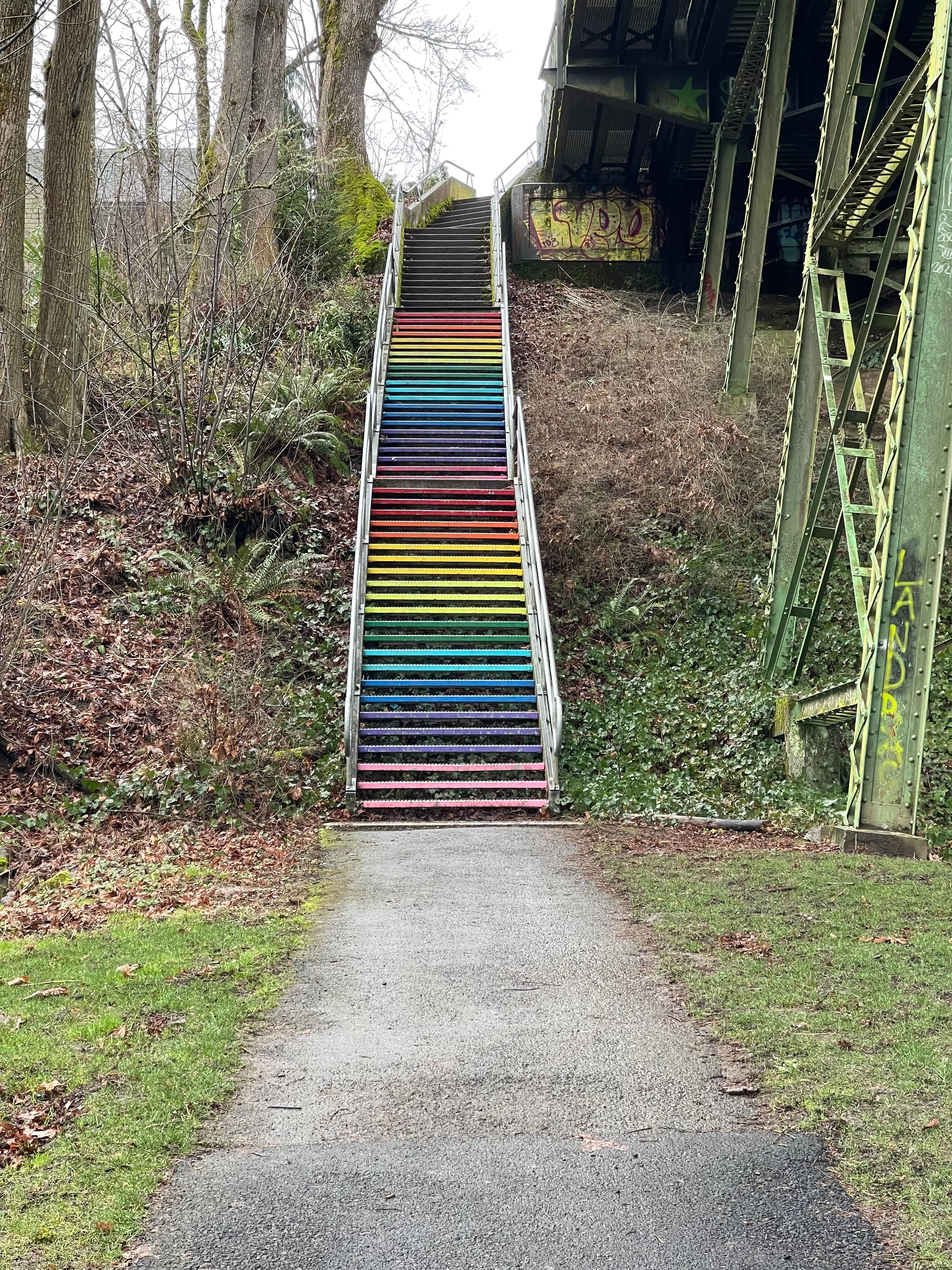 A rainbow staircase outside in nature leading up to a building.