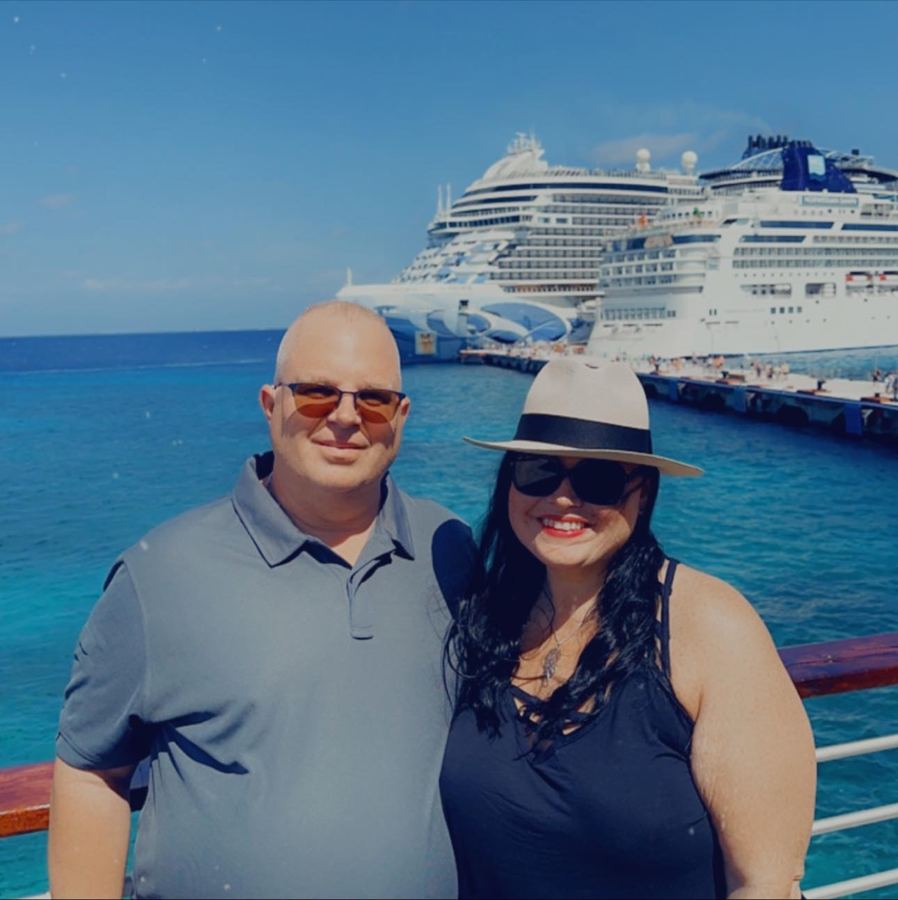 Advisor and wife posing in the sun with a cruise ship in the background