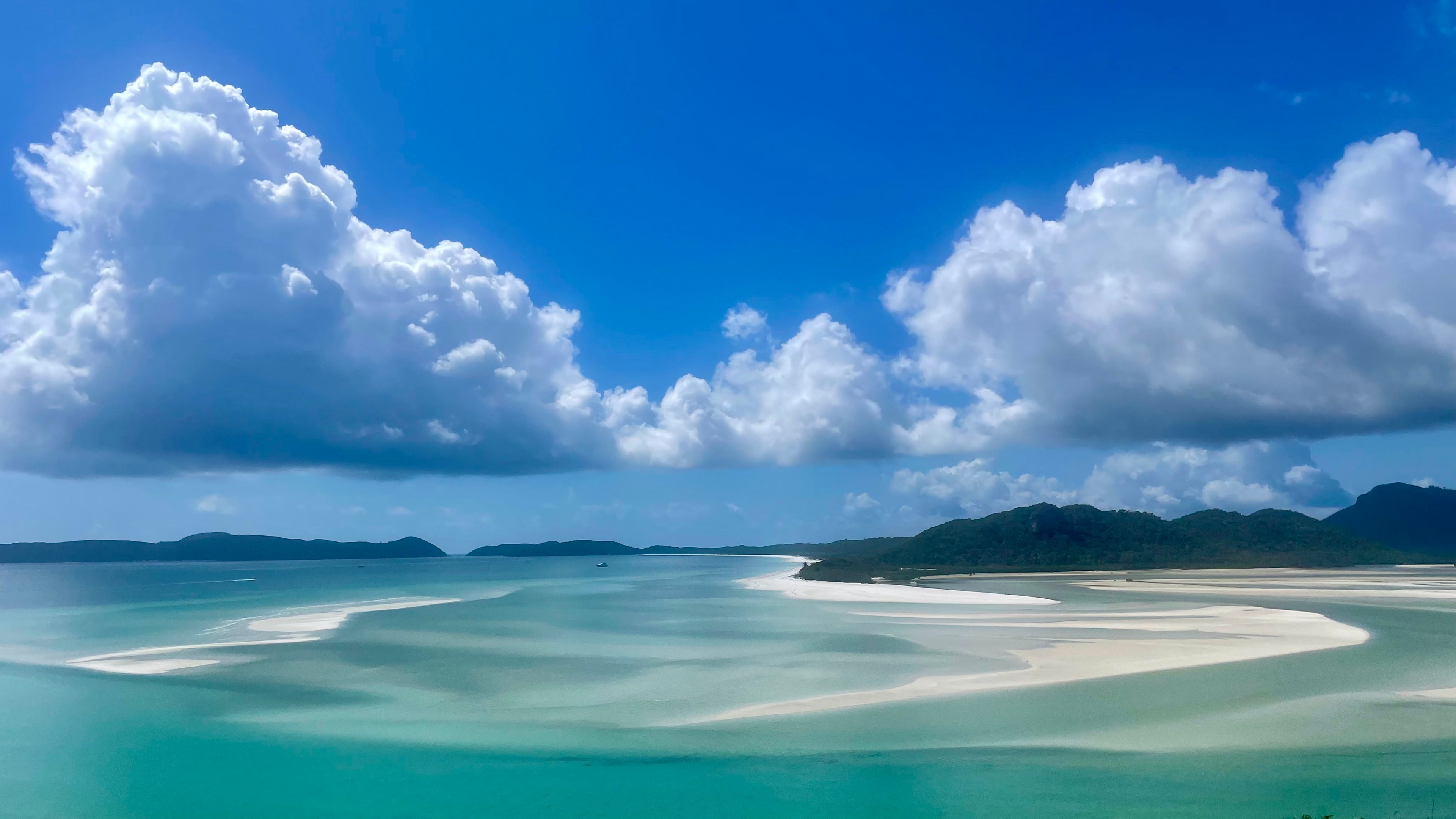 Beautiful view of a vast turquoise bay with waves approaching the shore under sunny skies