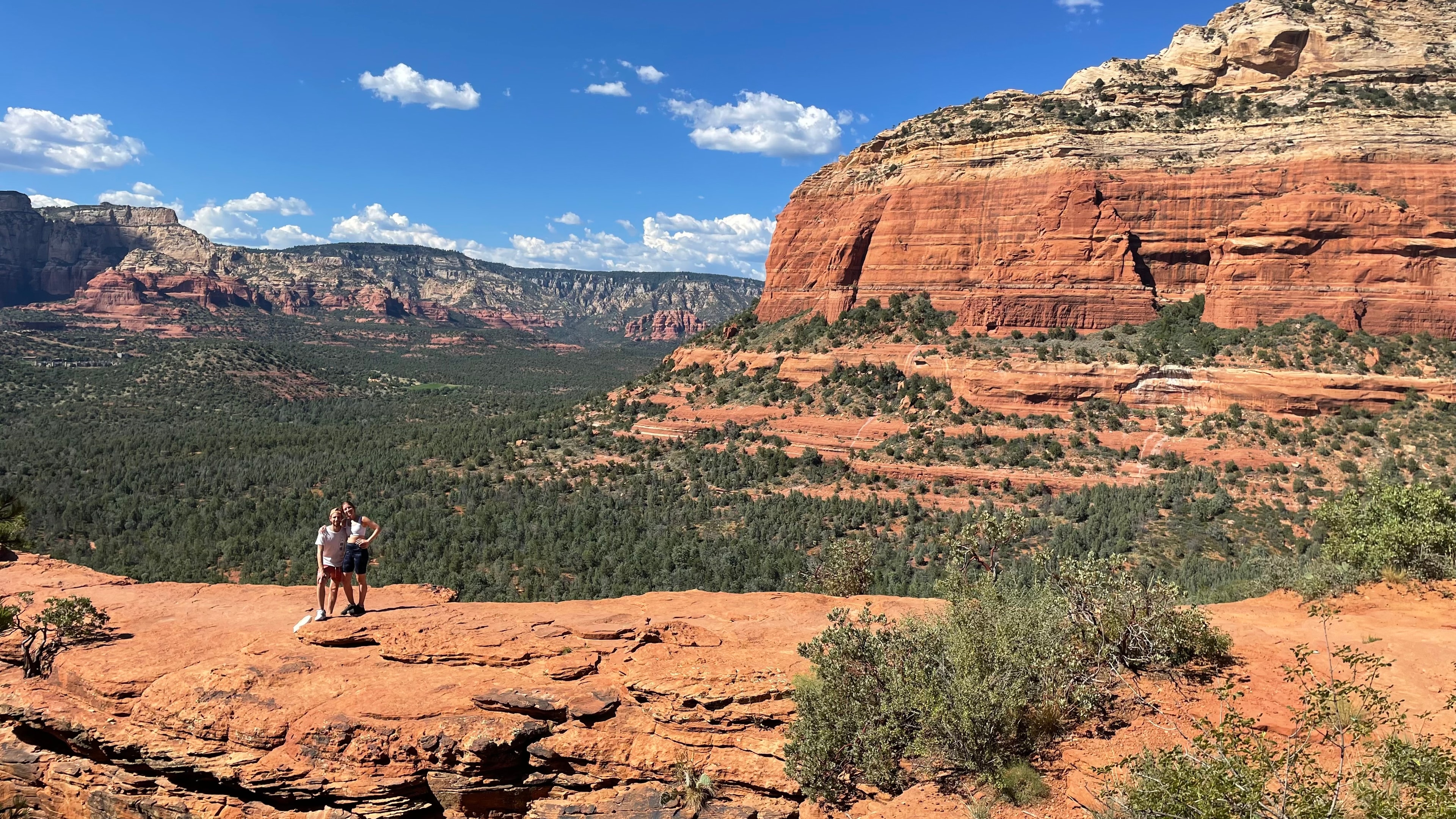 View of advisor and another person side by side on a hike through a red rock canyon on a sunny day