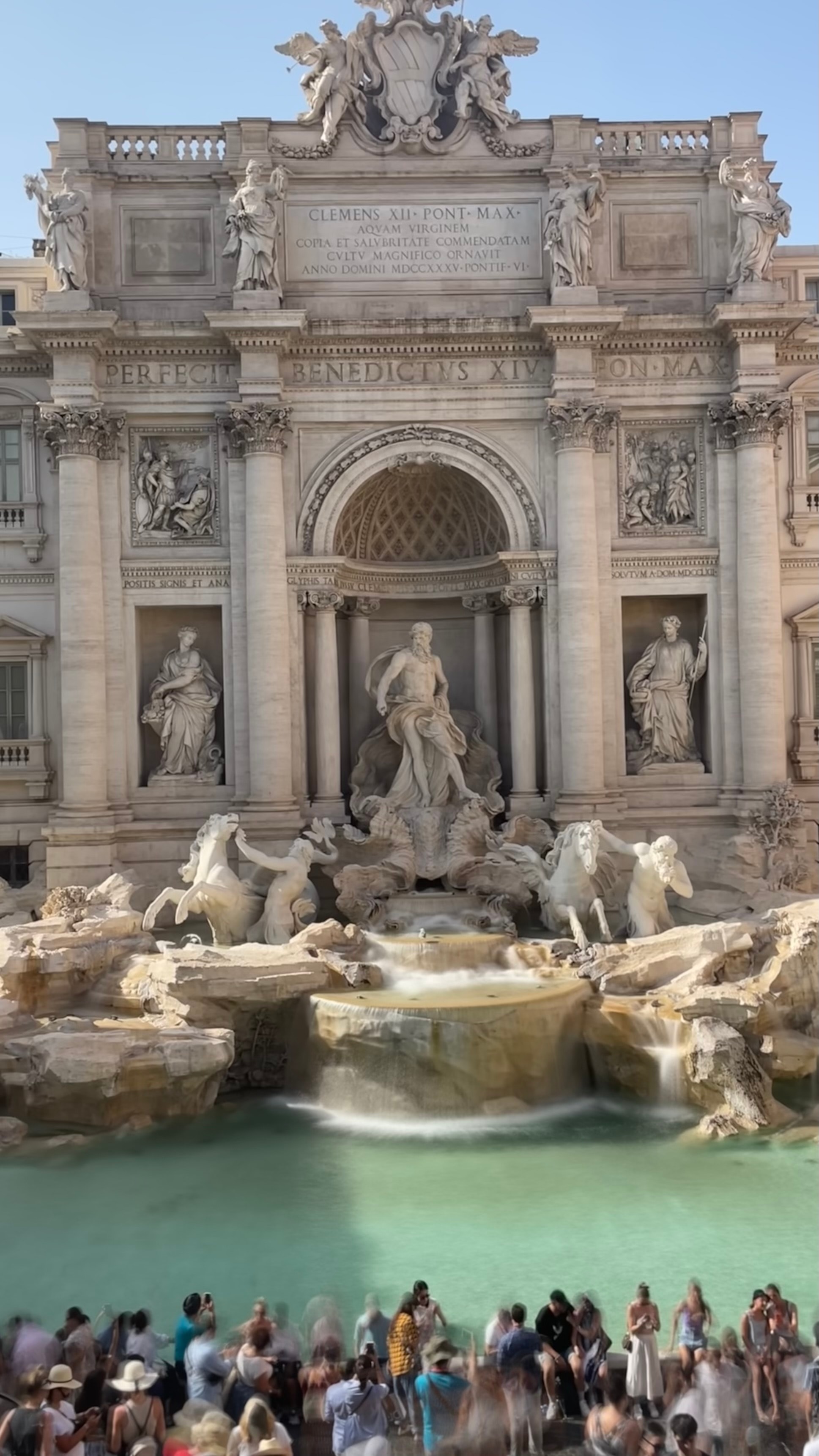 View of the Trevi Fountain with a crowd of tourists in front on a sunny day