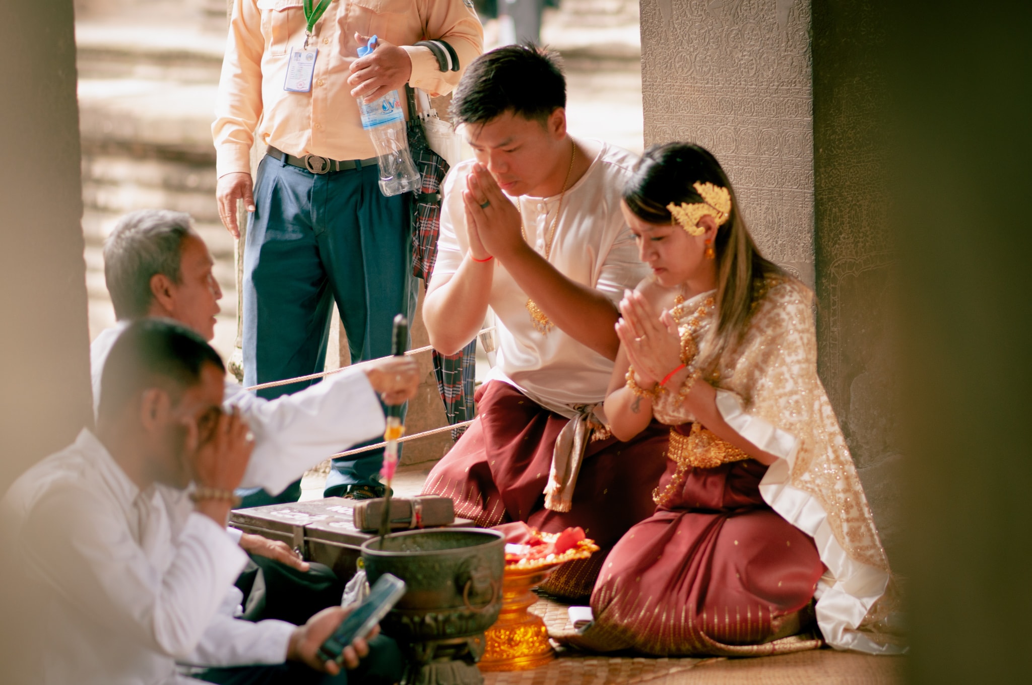 Advisor and a man kneeling side by side with hands in prayer position at a ceremony 