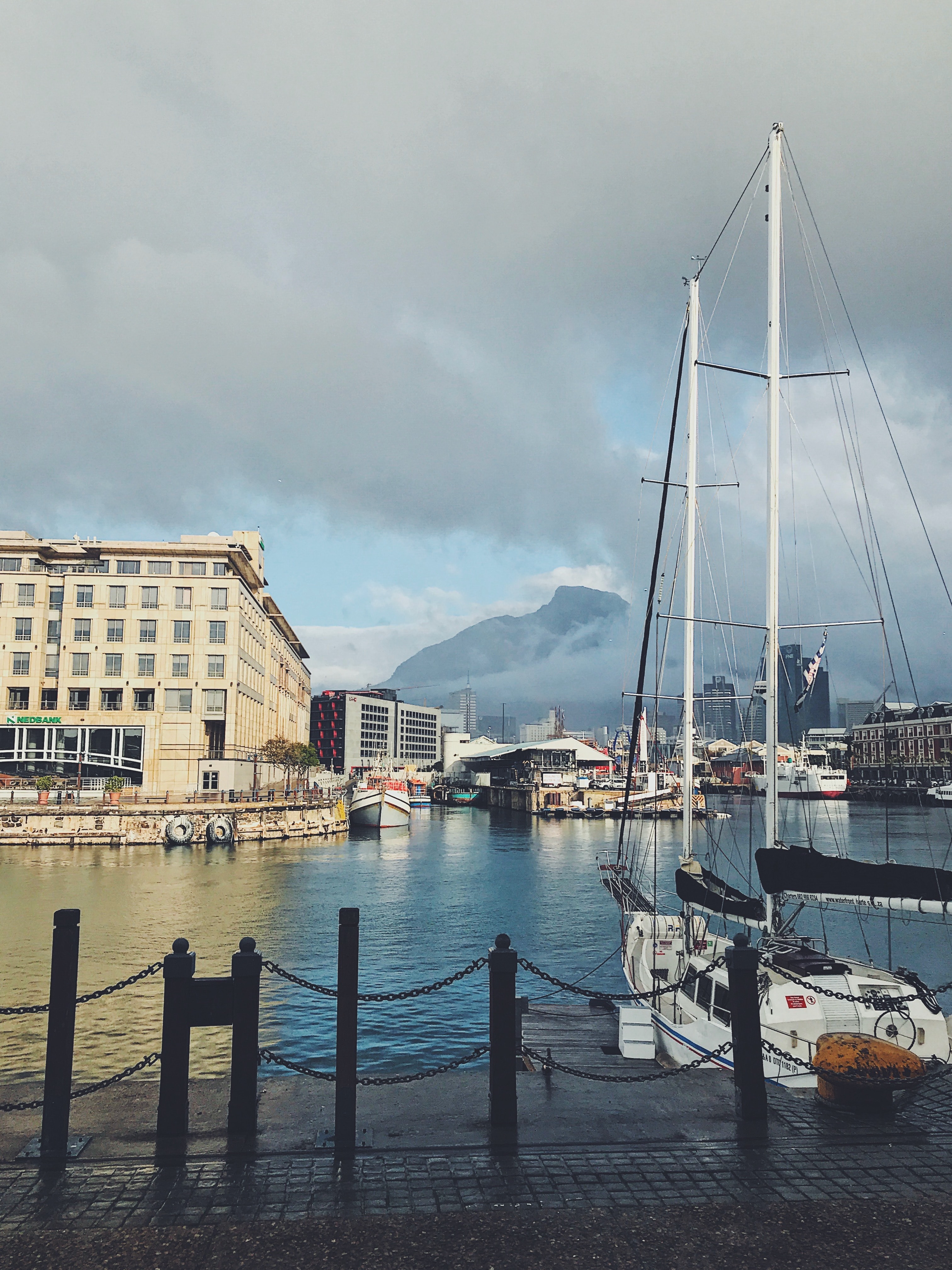 View of a city marina with a mountain obscured in clouds in the distance