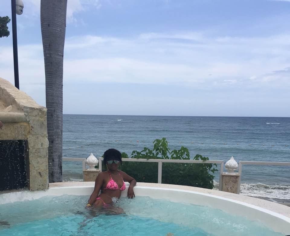 Advisor in a pink bathing suit leaning against the edge of an infinity pool overlooking the sea