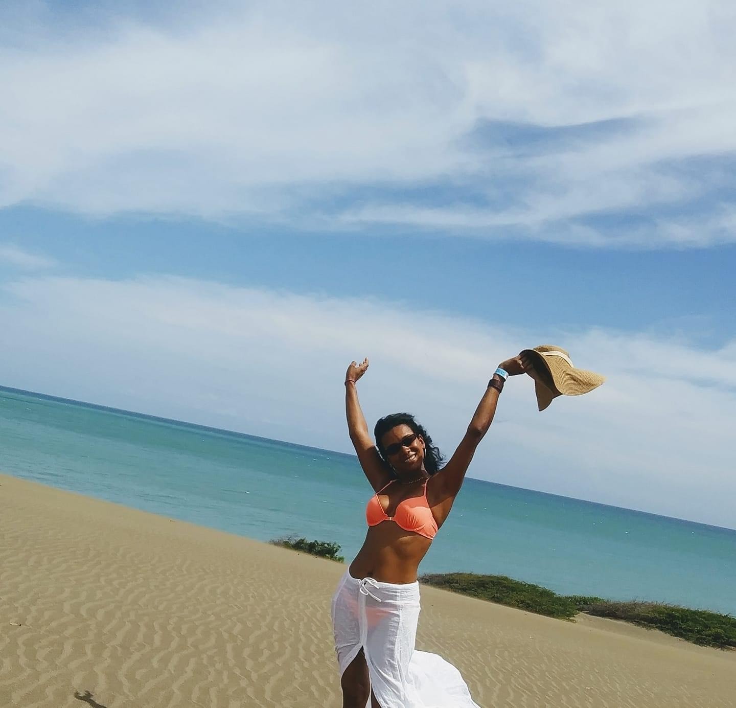 Advisor smiling with hands raised on a beautiful beach