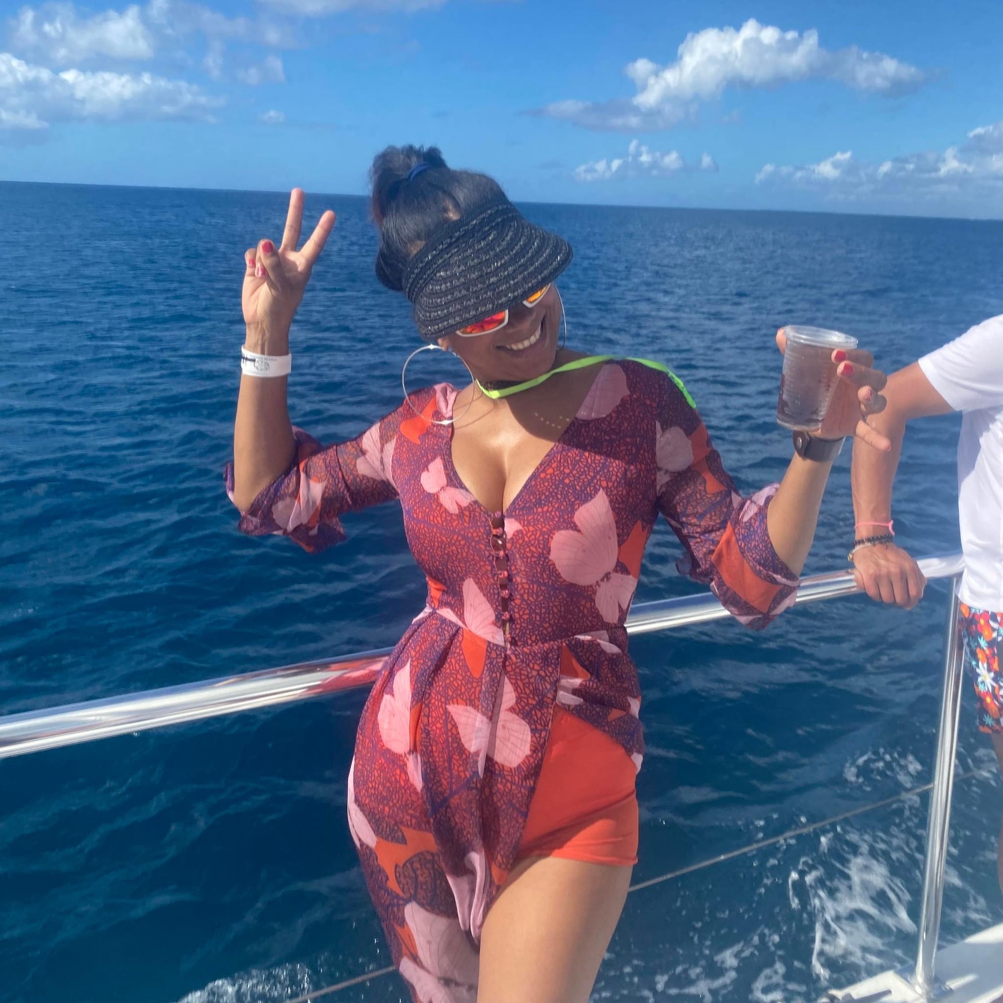 Advisor posing with a peace sign and a drink in the other hand on a boat