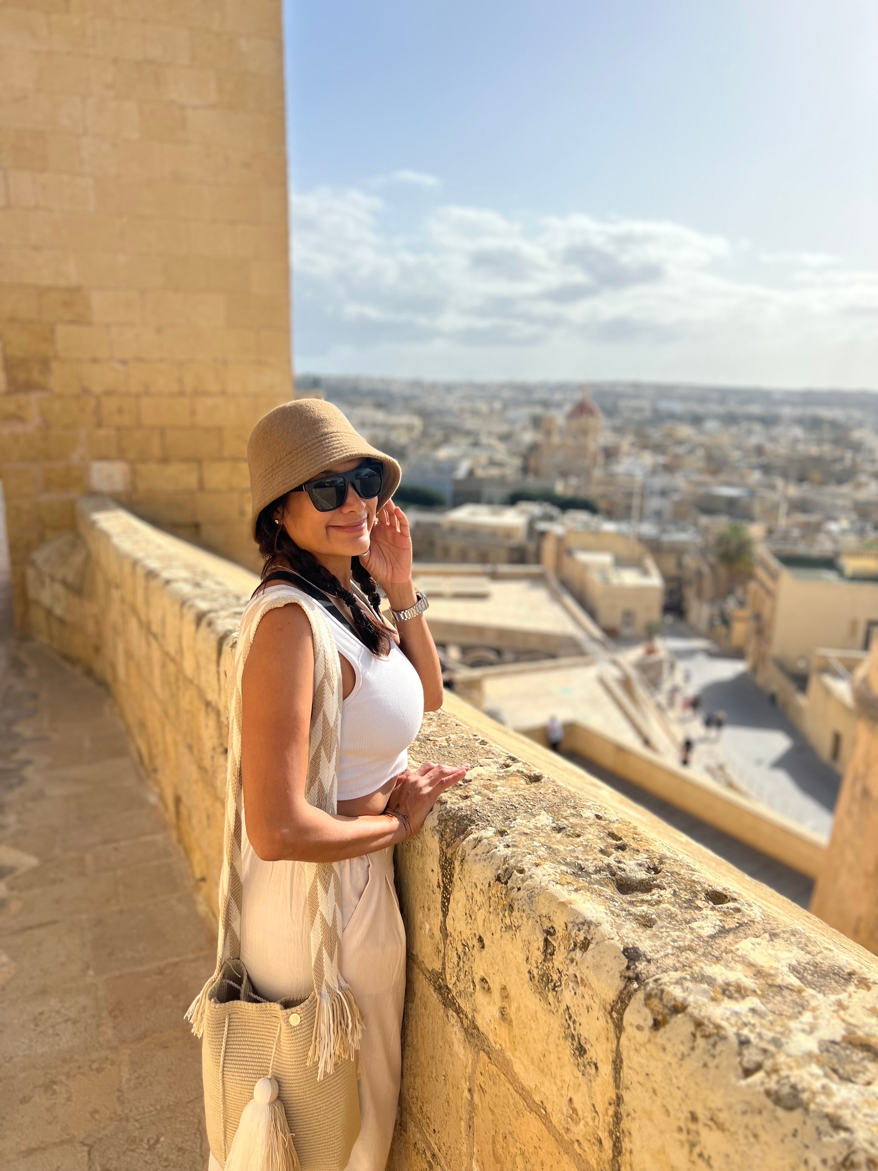 Advisor posing by a stone wall overlooking a city on a sunny day