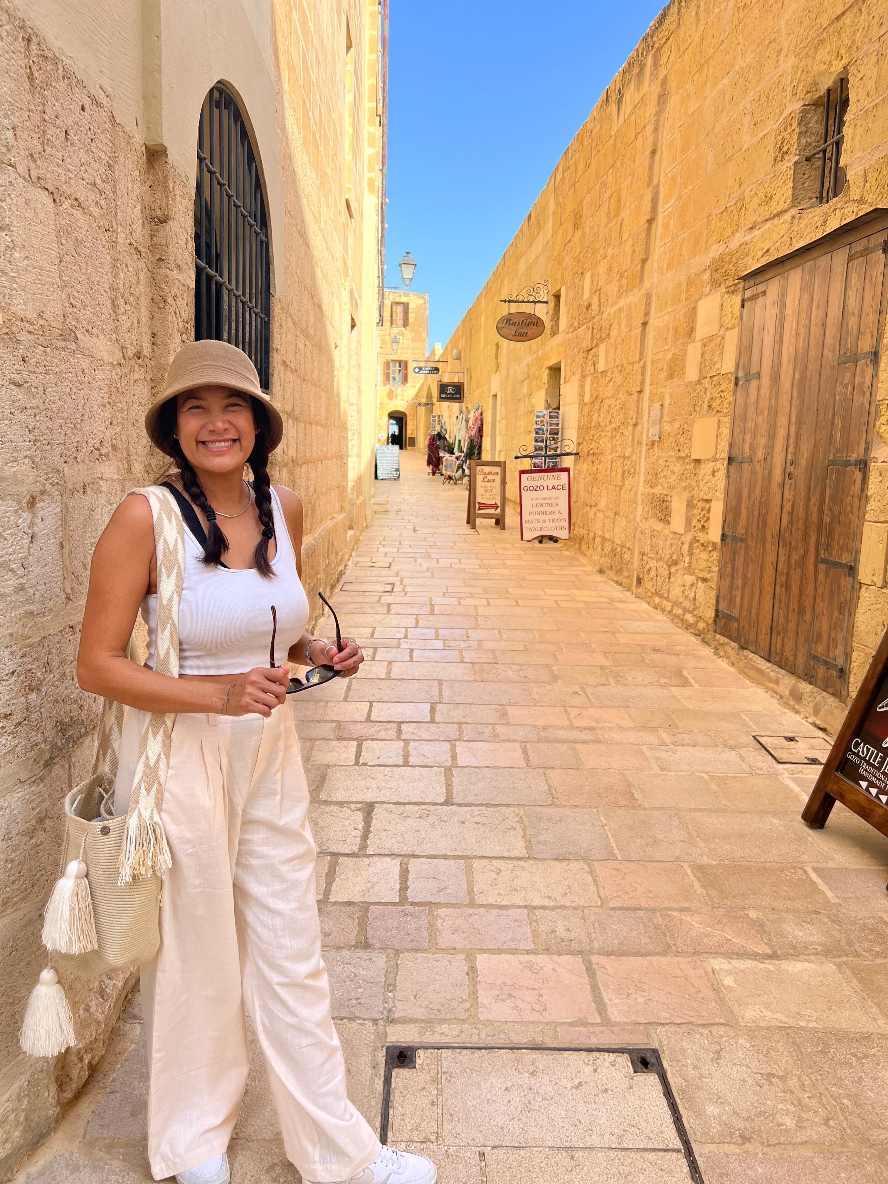 Advisor smiling for a photo on an empty, narrow stone street under clear skies