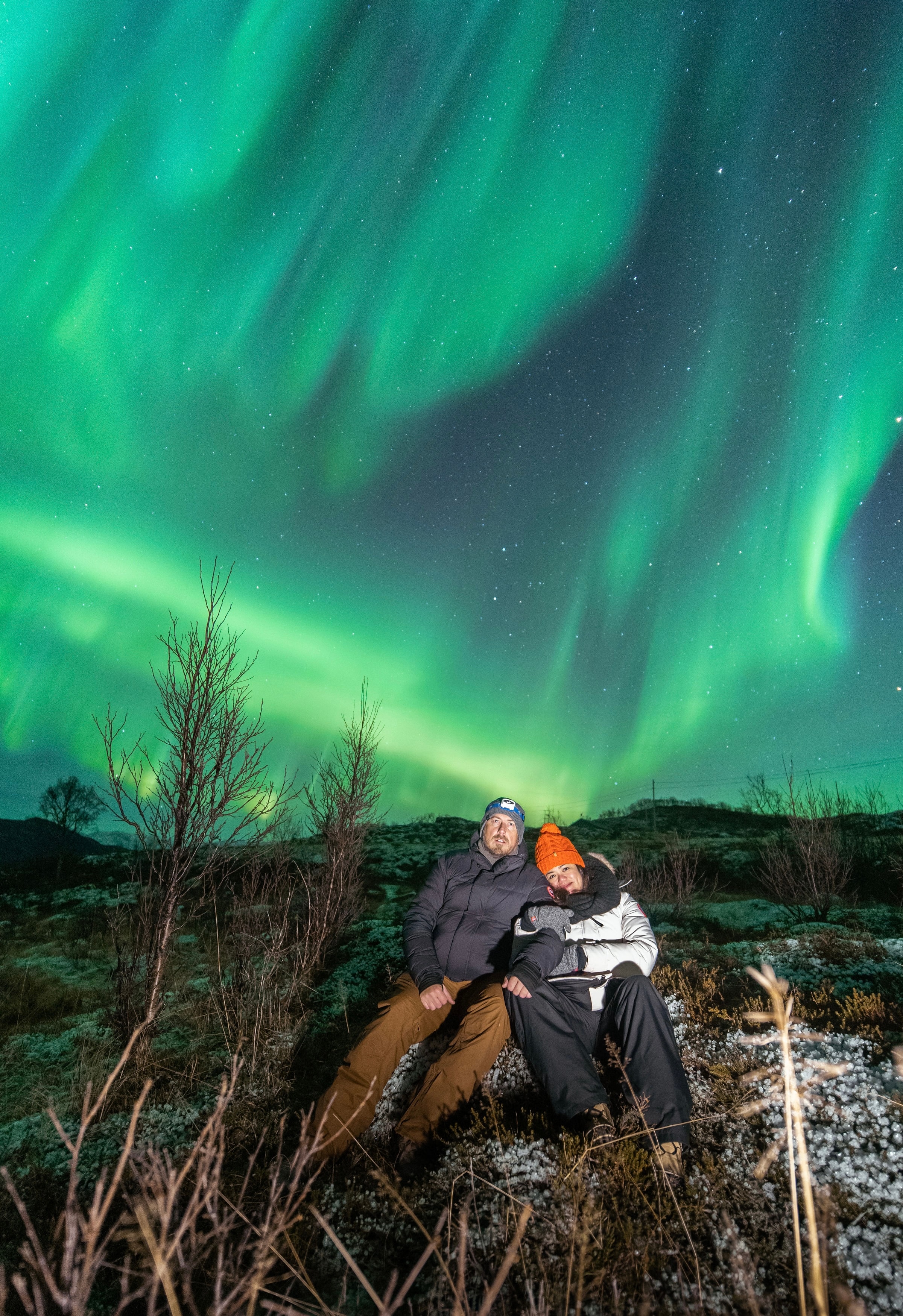 Advisor and partner sitting side by side under an amazing display of green aurora borealis lights