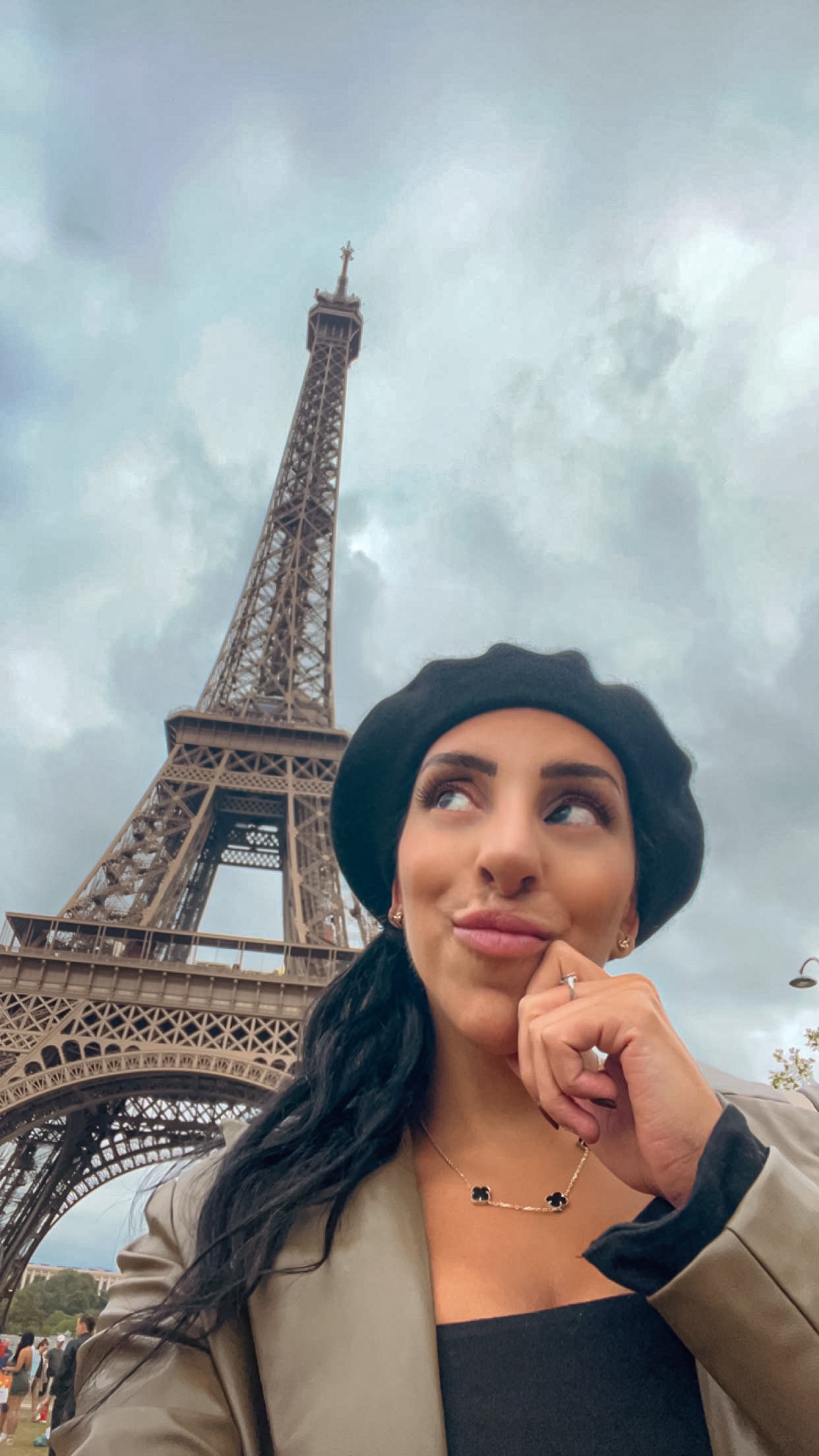 Advisor in a black beret taking a selfie in front of the Eiffel Tower on a cloudy day