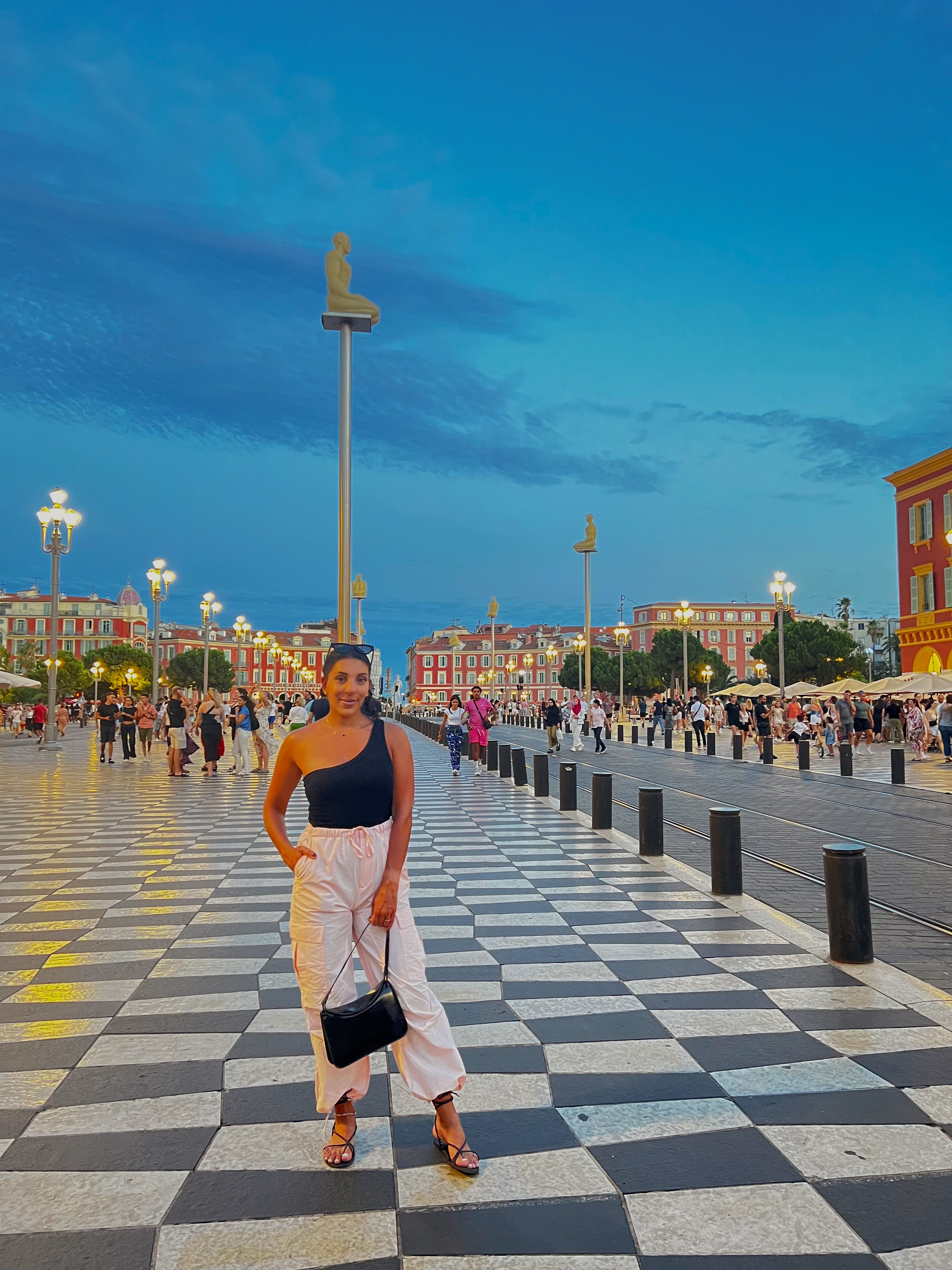 Advisor posing on a black and white tiled city plaza at dusk