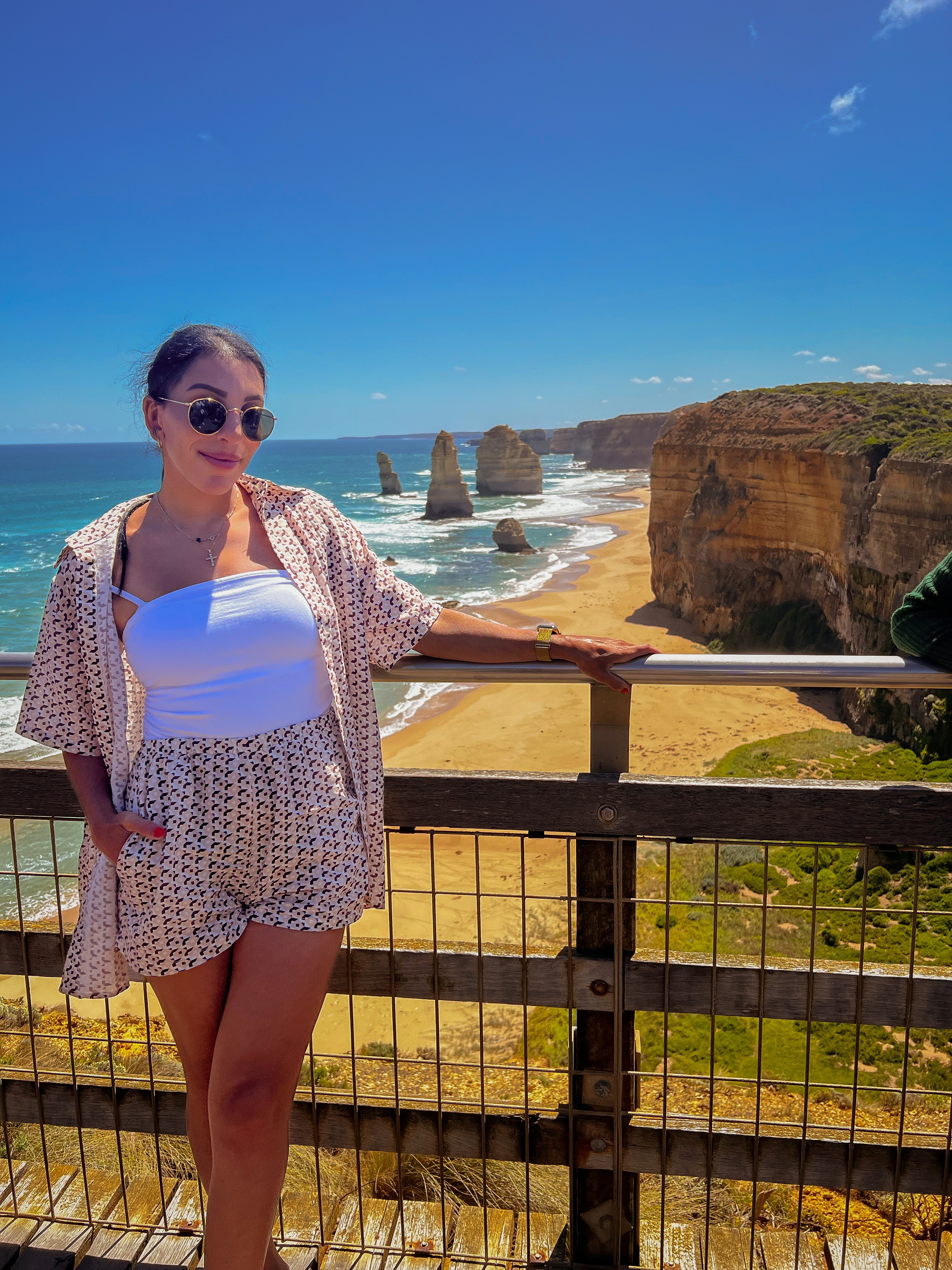 Advisor posing on a bridge overlooking a beautiful beach and coastal area under clear skies