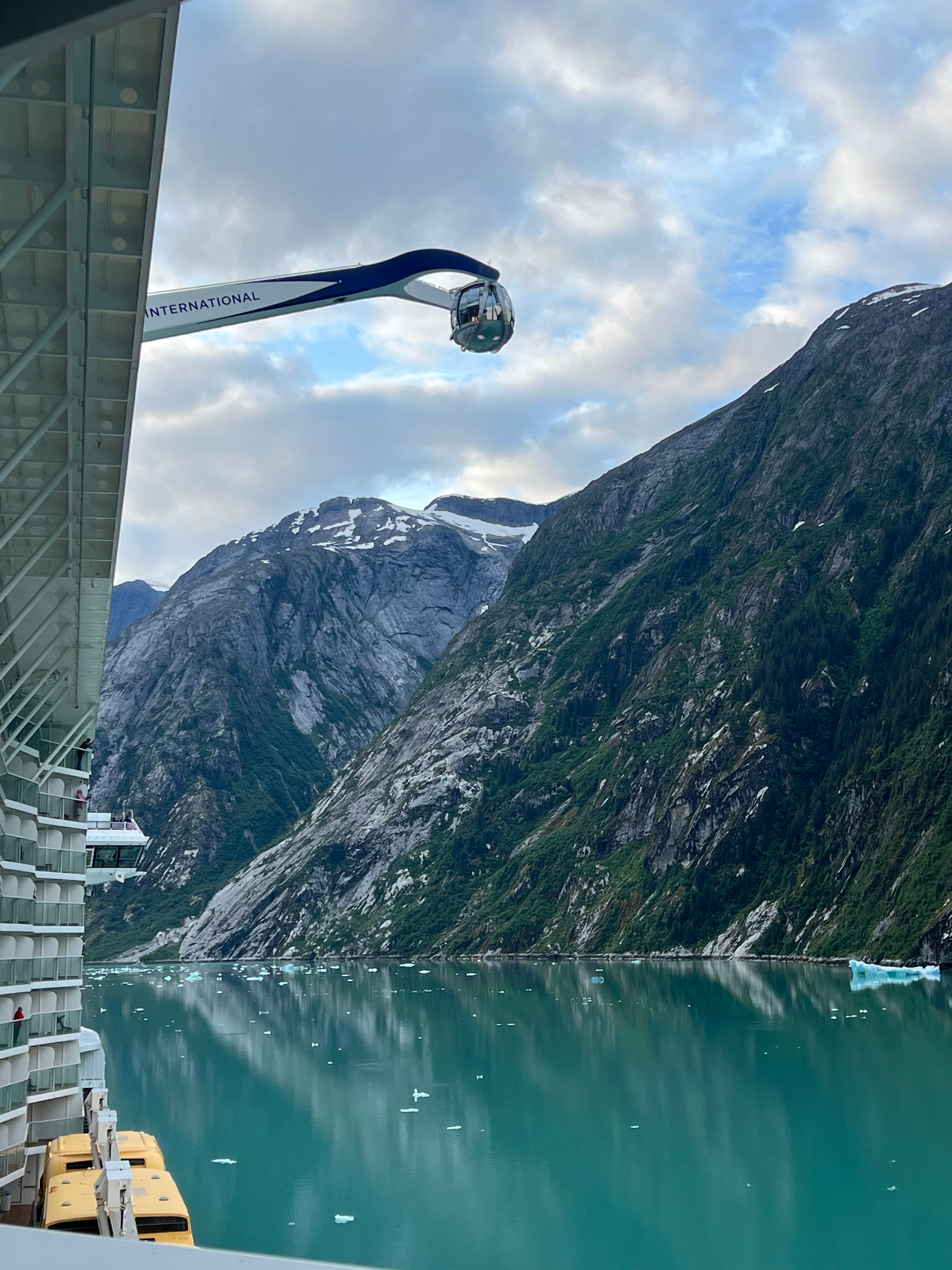 View of a glacial lake surrounded by snowy mountains seen from the side of a ship