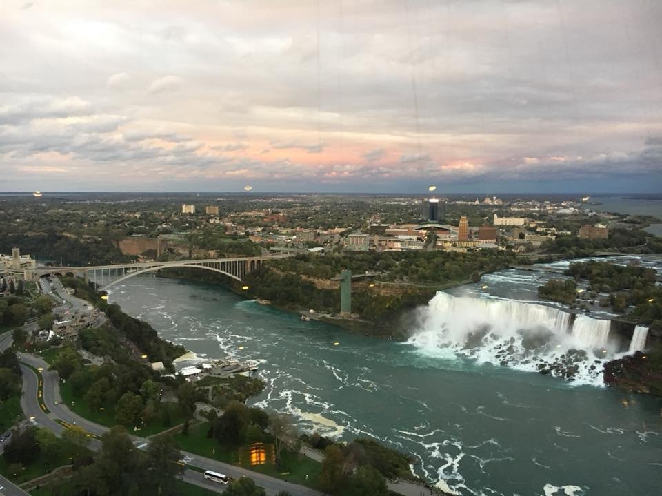 Overhead view of a city by a river with large waterfall pouring down on a cloudy day