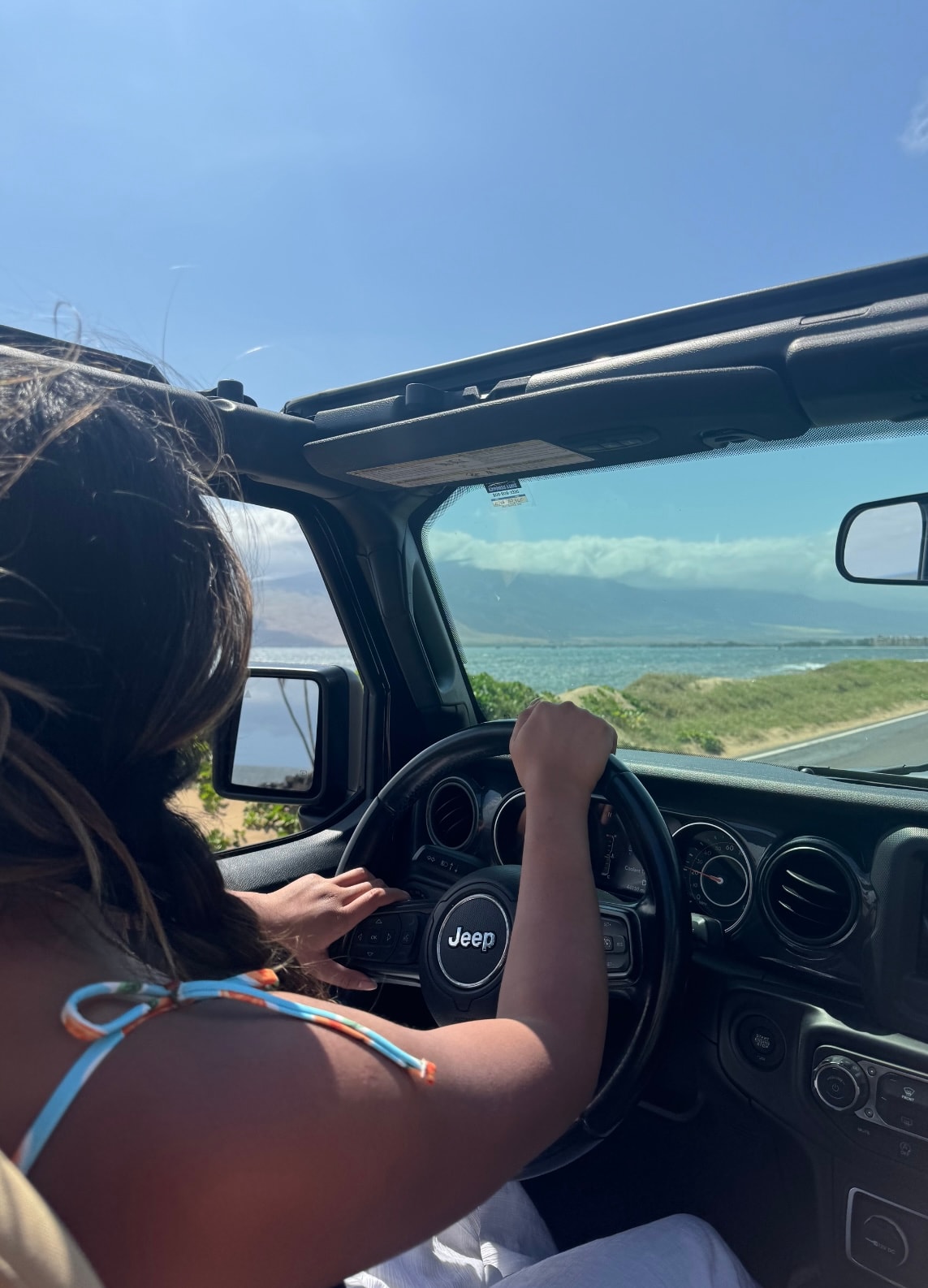 Advisor driving a jeep with the top down on a road by the sea on a clear day