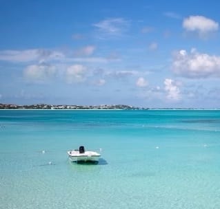 View of a small white boat floating in crystal clear ocean water on a sunny day