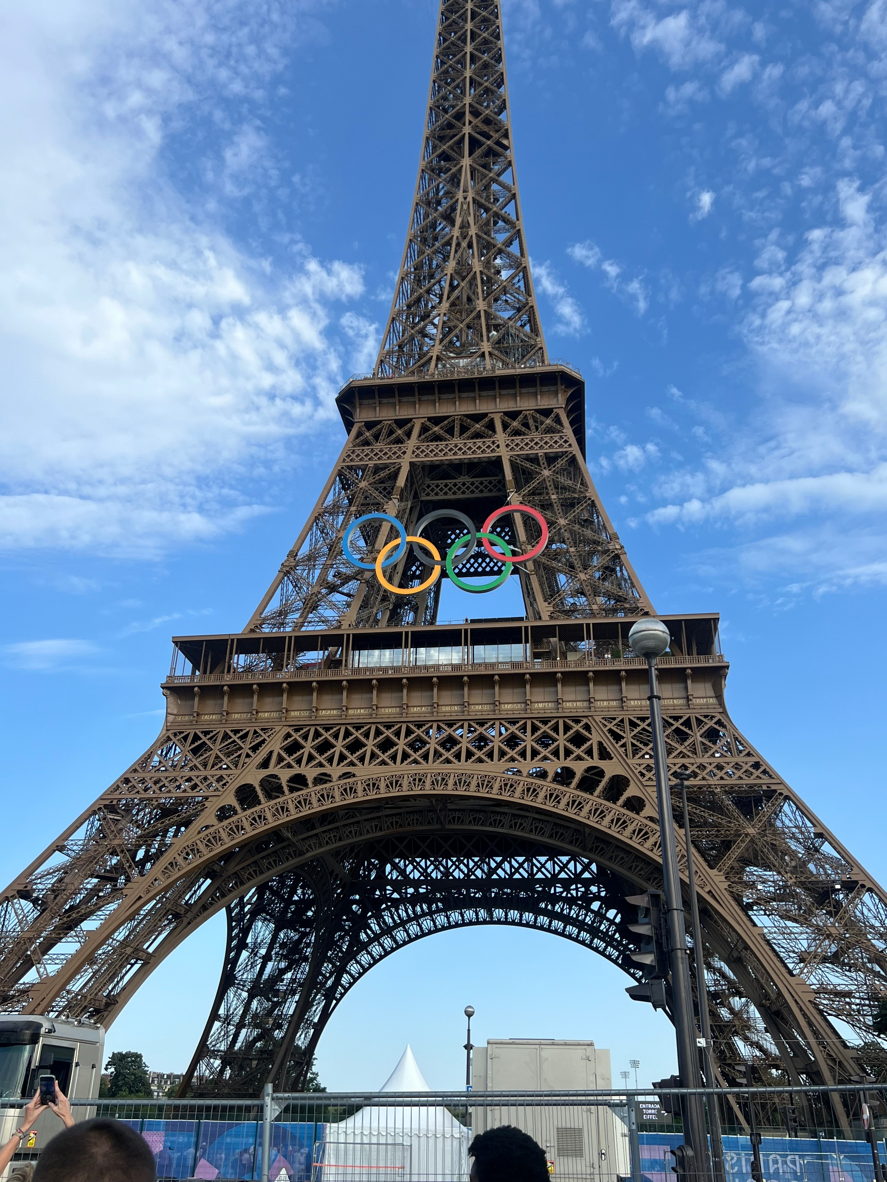 The Eiffel Tower with the Olympic Rings hanging in front on a sunny day